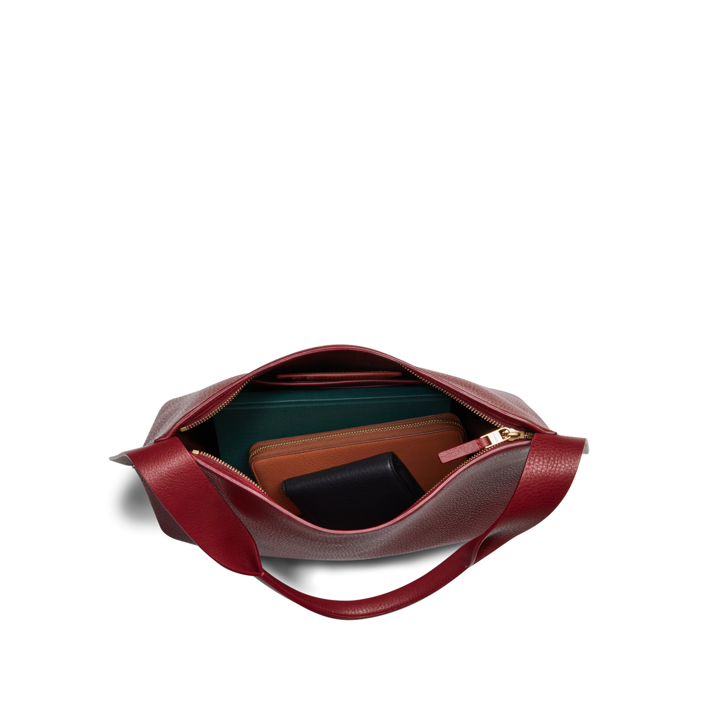 Top view of the Medium Derby Shoulder Bag - Ruby by Shinola in red leather with a zip, showing green, brown, and black wallets neatly arranged inside on a white background.