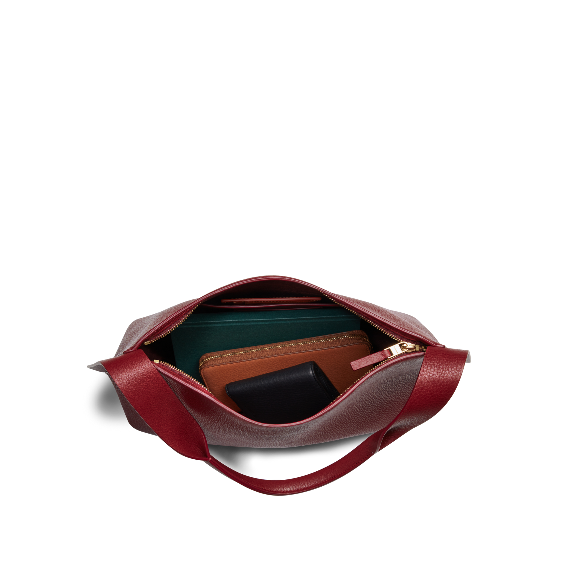 Top view of the Medium Derby Shoulder Bag - Ruby by Shinola in red leather with a zip, showing green, brown, and black wallets neatly arranged inside on a white background.