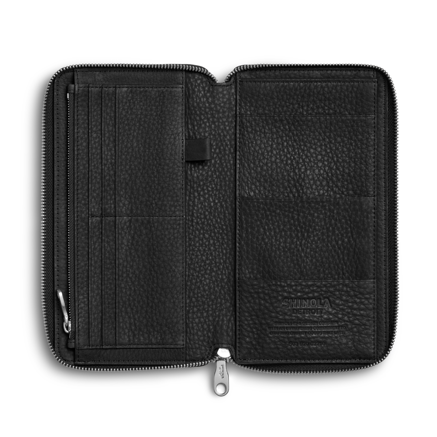 The Shinola Organizer Wallet - Black features natural grain leather, a zippered design, multiple left card slots, a central pen loop, and larger right pockets—perfect as a travel organizer or passport holder. "Shinola" is embossed on the lower right pocket.