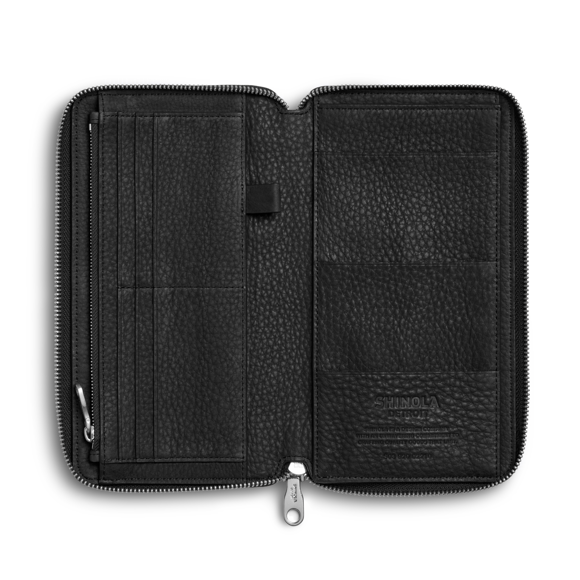 The Shinola Organizer Wallet - Black features natural grain leather, a zippered design, multiple left card slots, a central pen loop, and larger right pockets—perfect as a travel organizer or passport holder. "Shinola" is embossed on the lower right pocket.