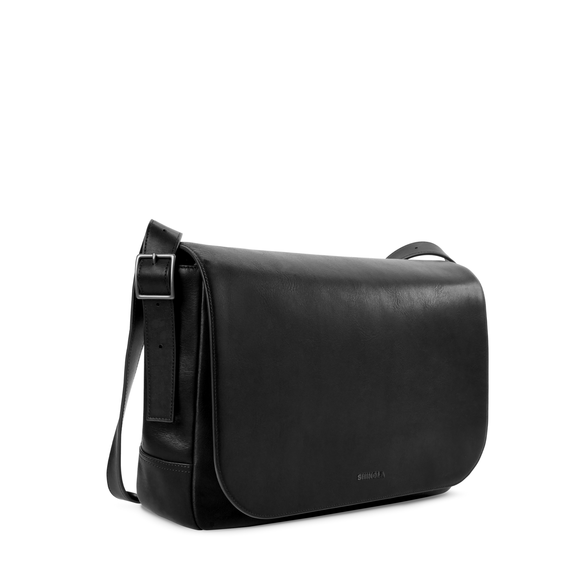 The Shinola Runwell Messenger Bag in sleek black leather features a large front flap, adjustable crossbody strap, minimal stitching, and padded laptop sleeve, shown against a plain white background.