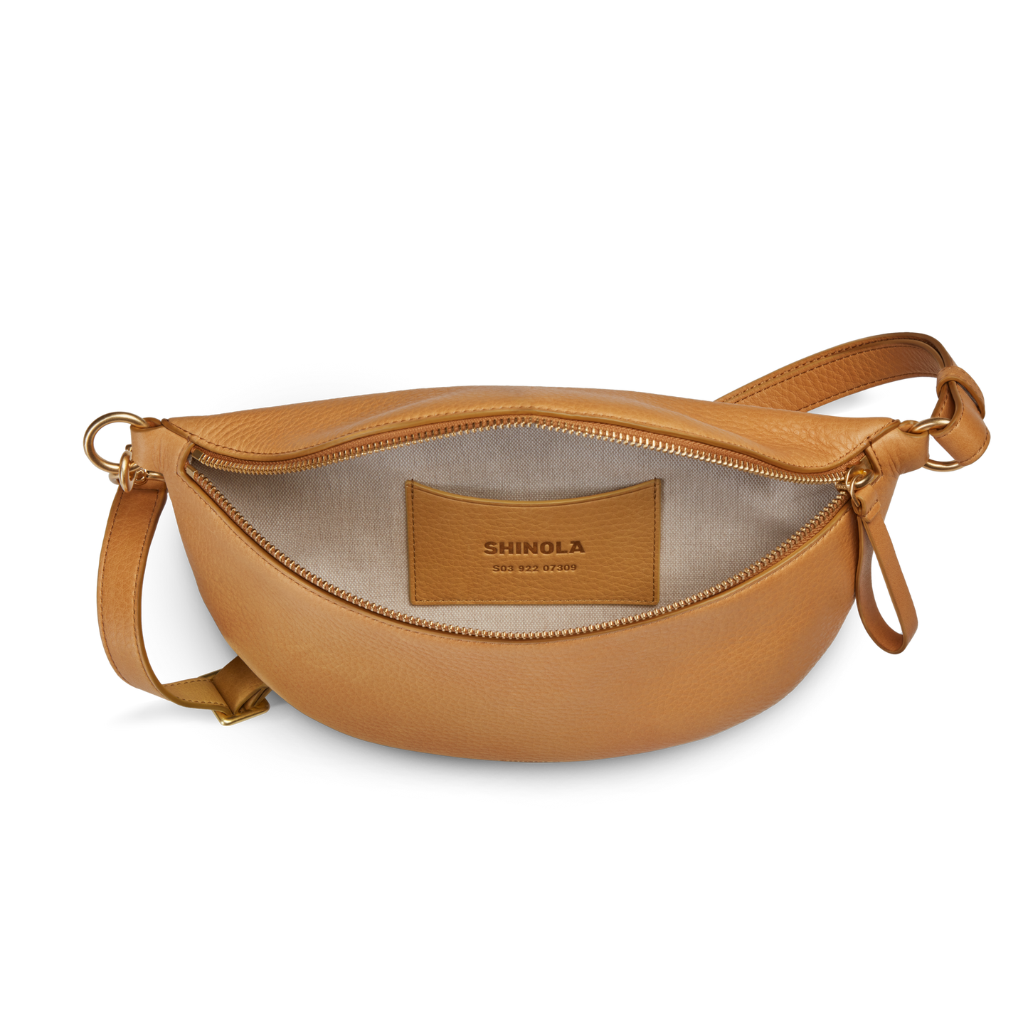 The Sling Bag - Honey by Shinola is a tan leather crossbody with an adjustable strap and gold hardware. It features a gold zipper, beige interior, and inner pocket labeled SHINOLA for a stylish, functional look.