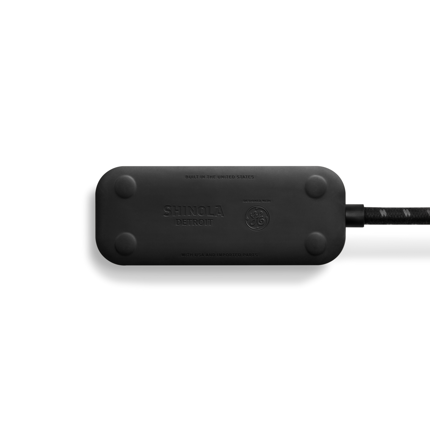 A black Shinola 2 Port Power Supply with rounded edges and a braided cord is shown from above on a white background. The Shinola logo appears, highlighting dual port quick charging for convenience.