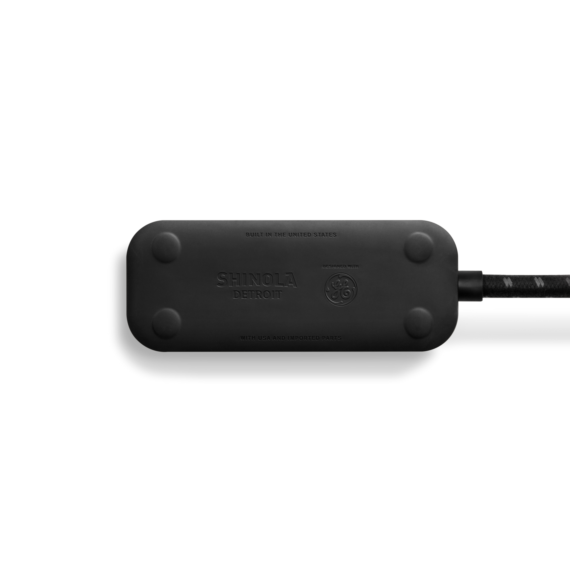 A black Shinola 2 Port Power Supply with rounded edges and a braided cord is shown from above on a white background. The Shinola logo appears, highlighting dual port quick charging for convenience.