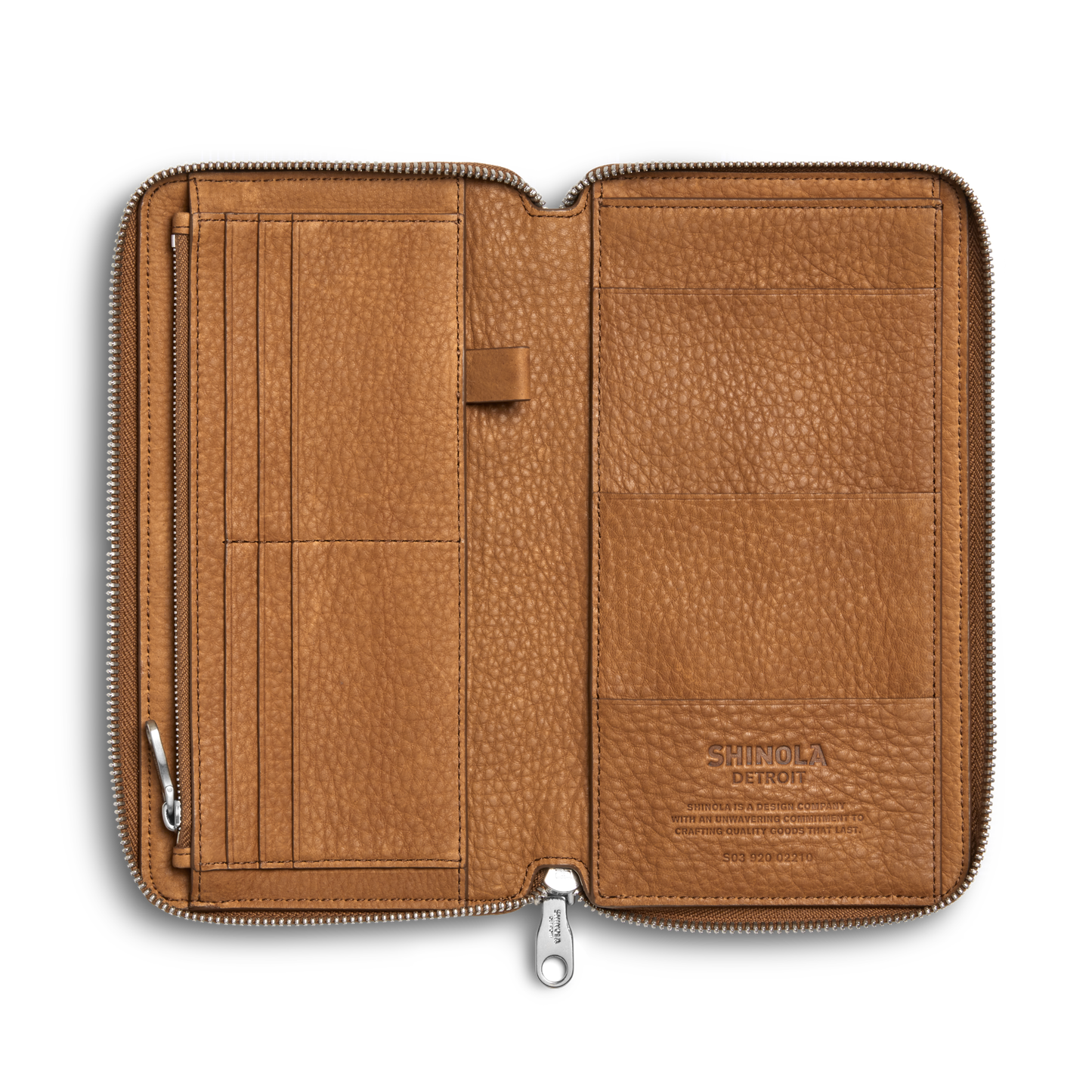 The Shinola Organizer Wallet - Tan is a zip-around wallet in natural grain leather with multiple card slots, pockets, and a pen loop. "Shinola" is stamped inside on the right. The empty wallet lies flat against a white background.