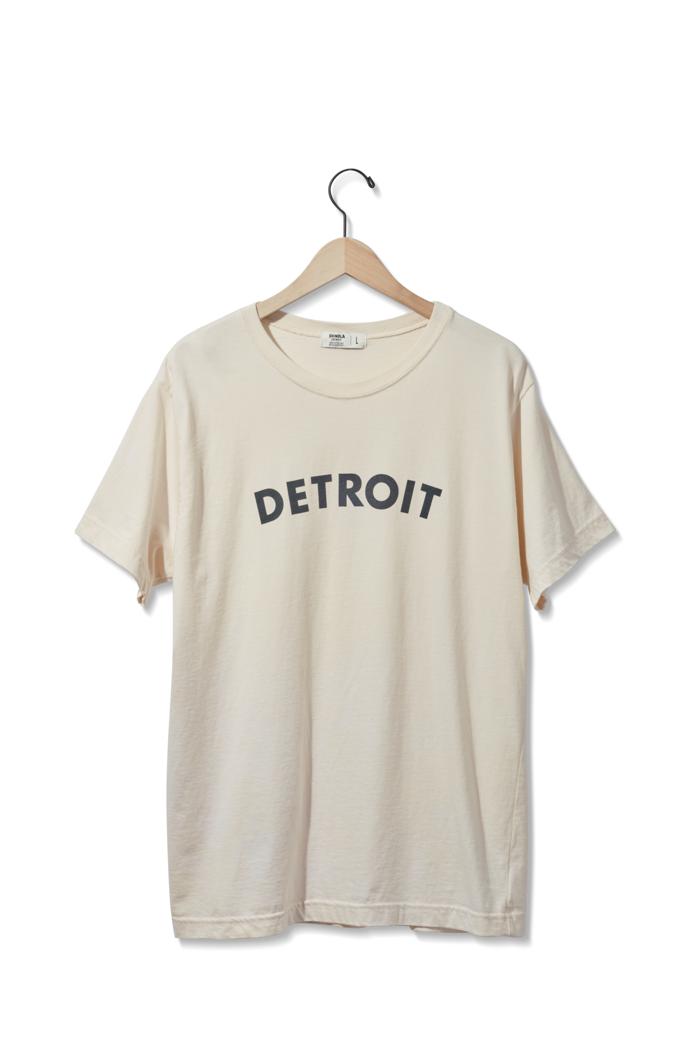 The Shinola Detroit Graphic T Shirt - Cream features bold black "DETROIT" lettering on the front and is displayed on a wooden hanger against a plain white background.