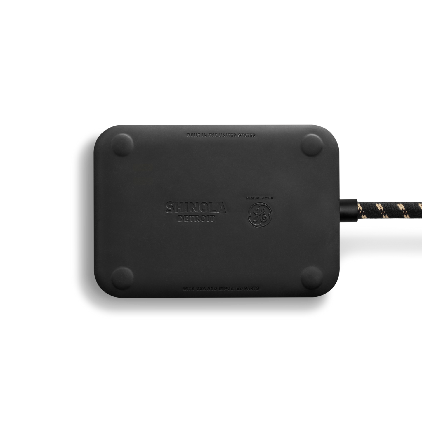 A rectangular Shinola 5 Port Power Supply - Tangerine with rounded corners sits on a white background. A braided black and gold USB A+C cable is attached to its right side. The device features the Shinola logo and branding.