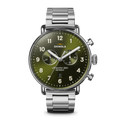 The Shinola Canfield Chronograph Watch - Dark Olive features a silver case, dark olive dial with white numerals, three subdials, and a stainless steel link band, shown against a white background.