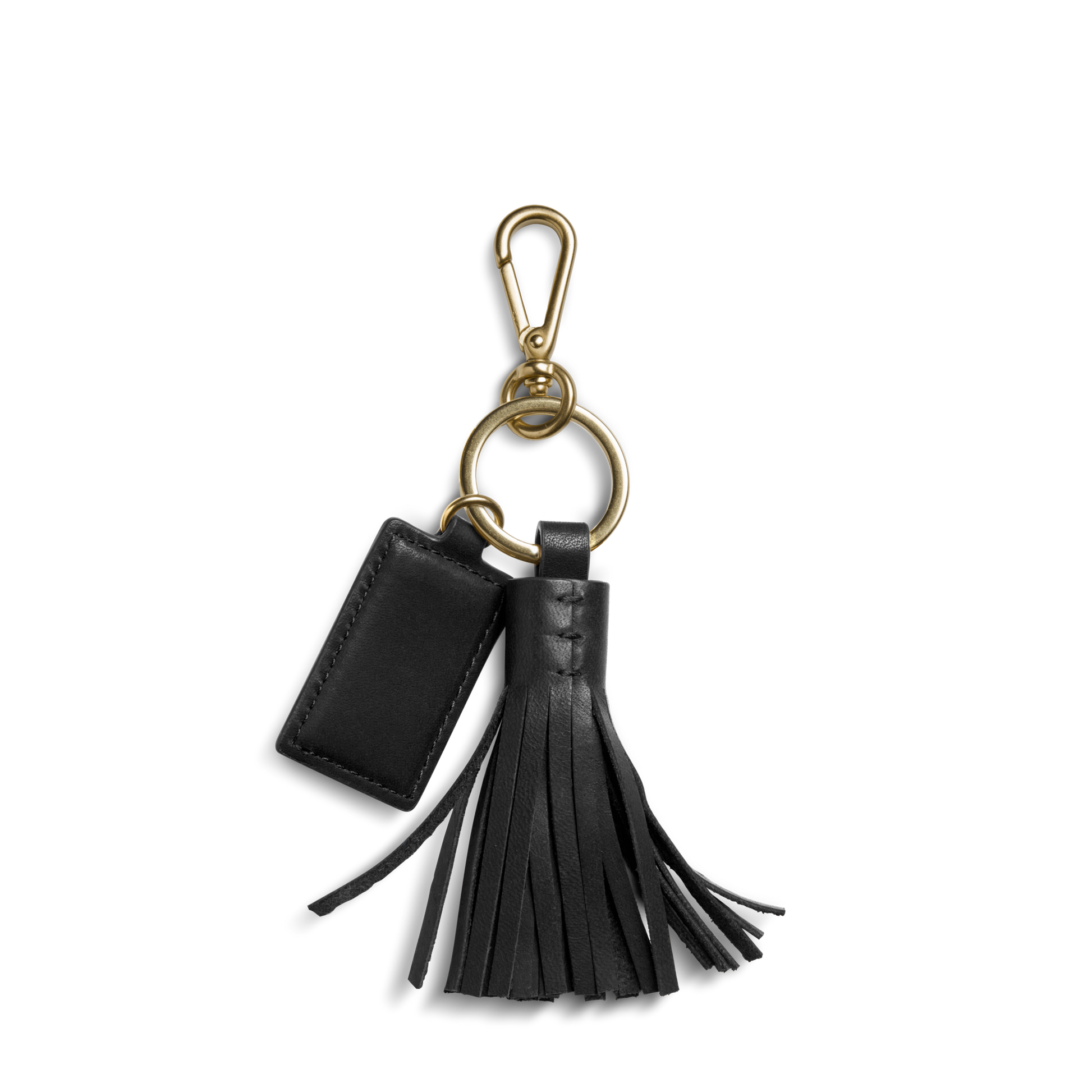 The Shinola Leather Tassel Keychain - Black features a black leather key fob with a gold clip, small rectangular tag, and decorative tassel on a gold keyring, displayed against a white background.