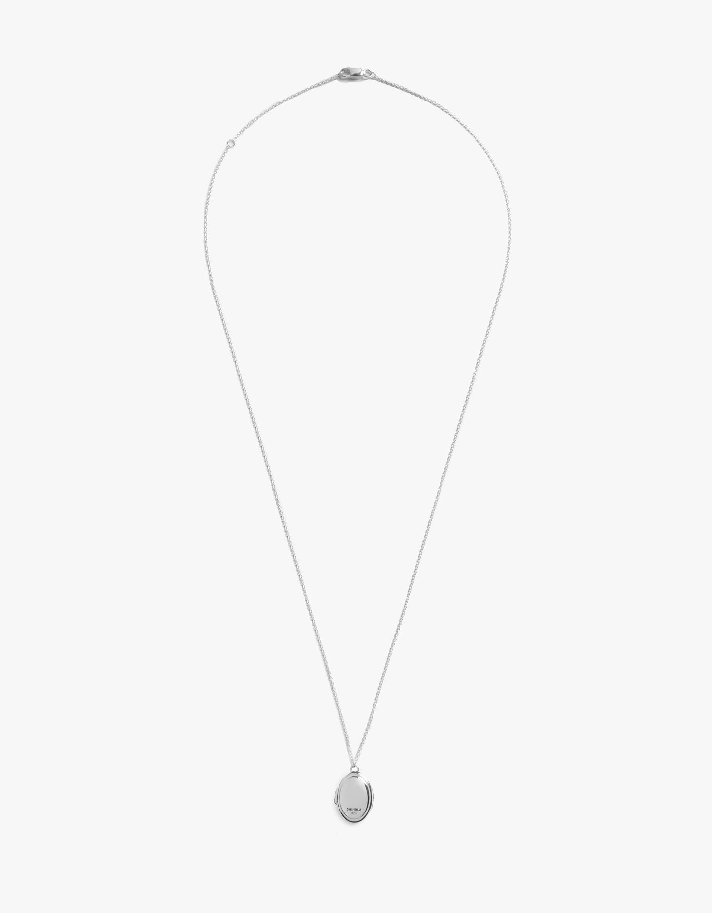 The Shinola Heirloom Petite Locket Necklace features a delicate sterling silver chain and a small, round engraved pendant, displayed against a plain white background.