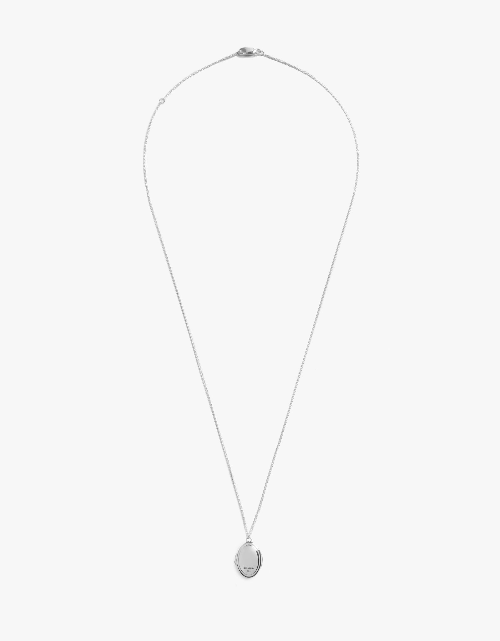 The Shinola Heirloom Petite Locket Necklace features a delicate sterling silver chain and a small, round engraved pendant, displayed against a plain white background.
