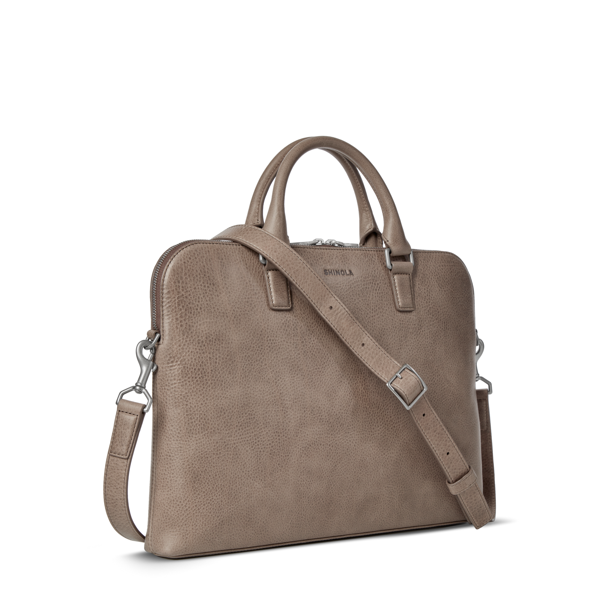 The Shinola Portfolio Briefcase - Stone is a taupe leather bag with double handles, detachable shoulder strap, silver hardware, and a subtle front logo—ideal as a slim laptop briefcase for modern professionals.