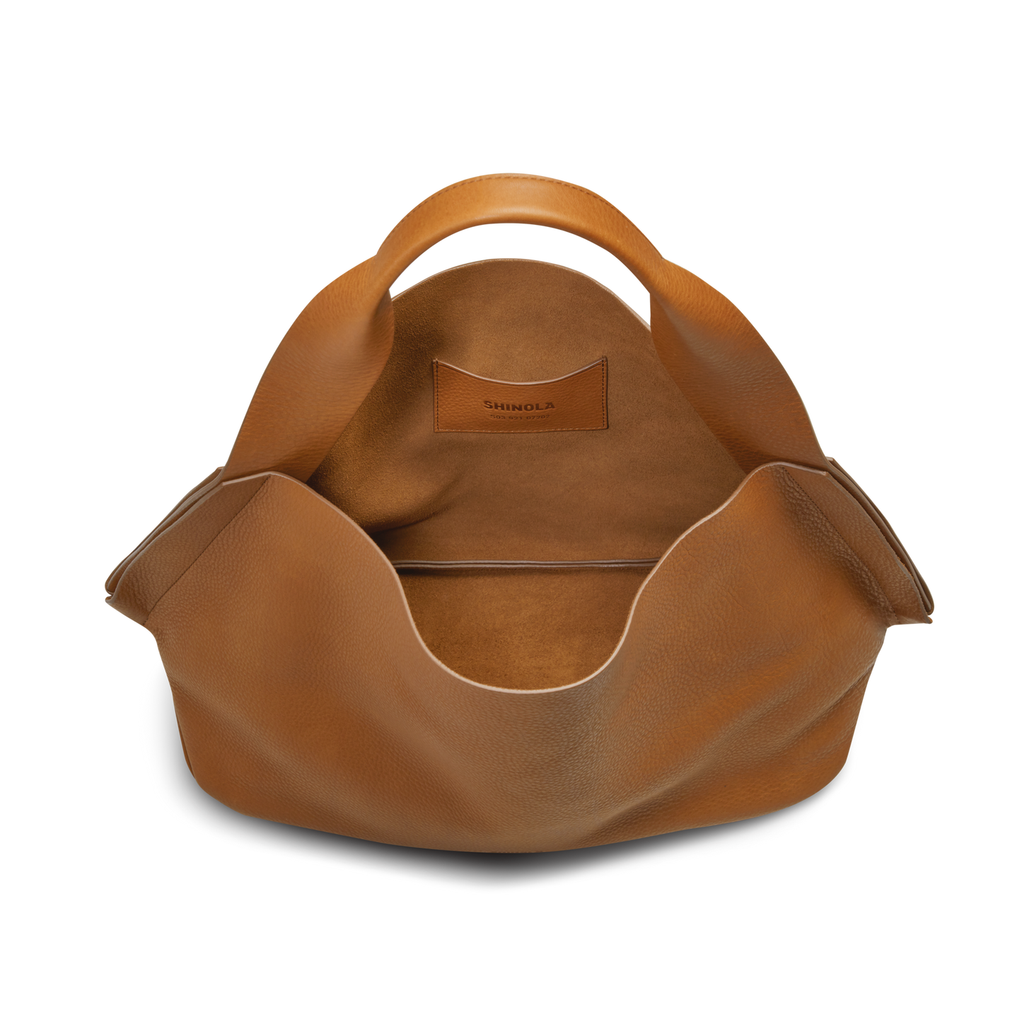 The Shinola Derby Shoulder Bag - Tan features curved carrying handles, a spacious interior lined with matching leather, and the brand name visible on an inner card pocket.