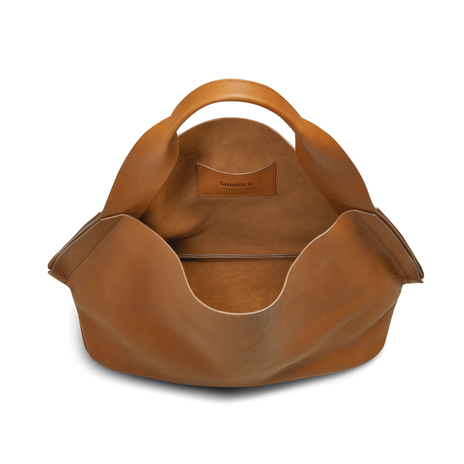 The Shinola Derby Shoulder Bag - Tan features curved carrying handles, a spacious interior lined with matching leather, and the brand name visible on an inner card pocket.