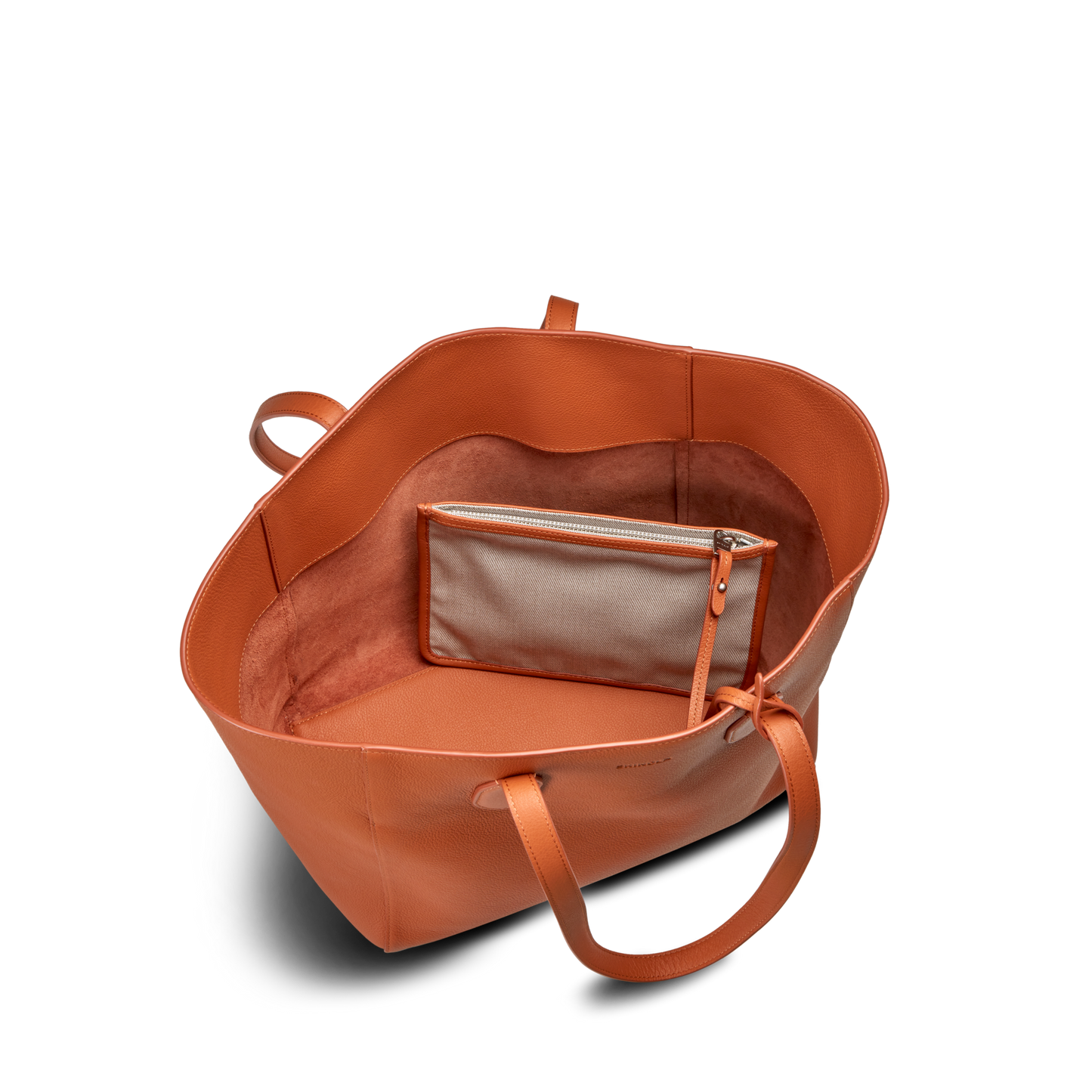The Shinola Runabout Tote Bag - Rust features a large orange pebbled leather design with two handles, an open spacious interior, and an attached small beige zipper pouch inside.