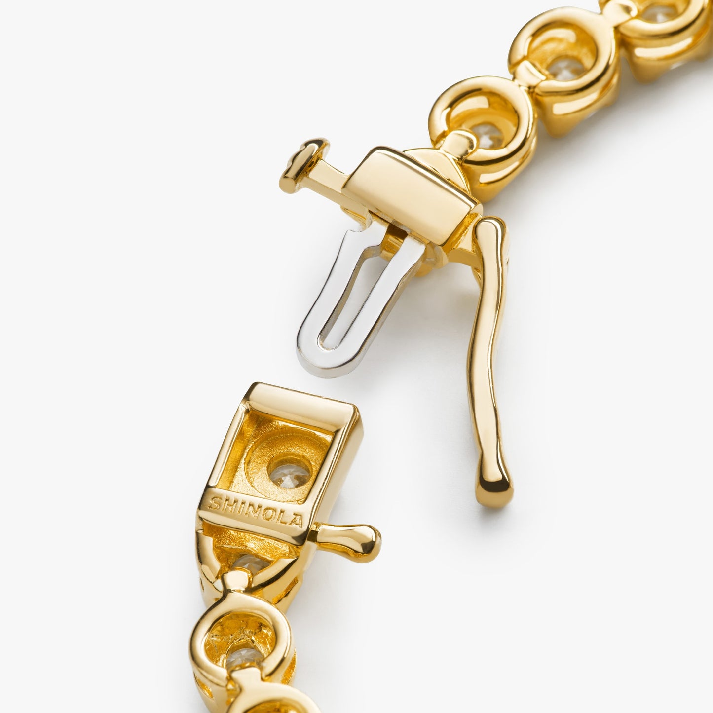 Close-up of the 4 Carat 7" Diamond Tennis Bracelet in yellow gold by Shinola, showcasing its interlocking links, secure clasp with engraved branding, and classic tennis bracelet elegance against a white background.