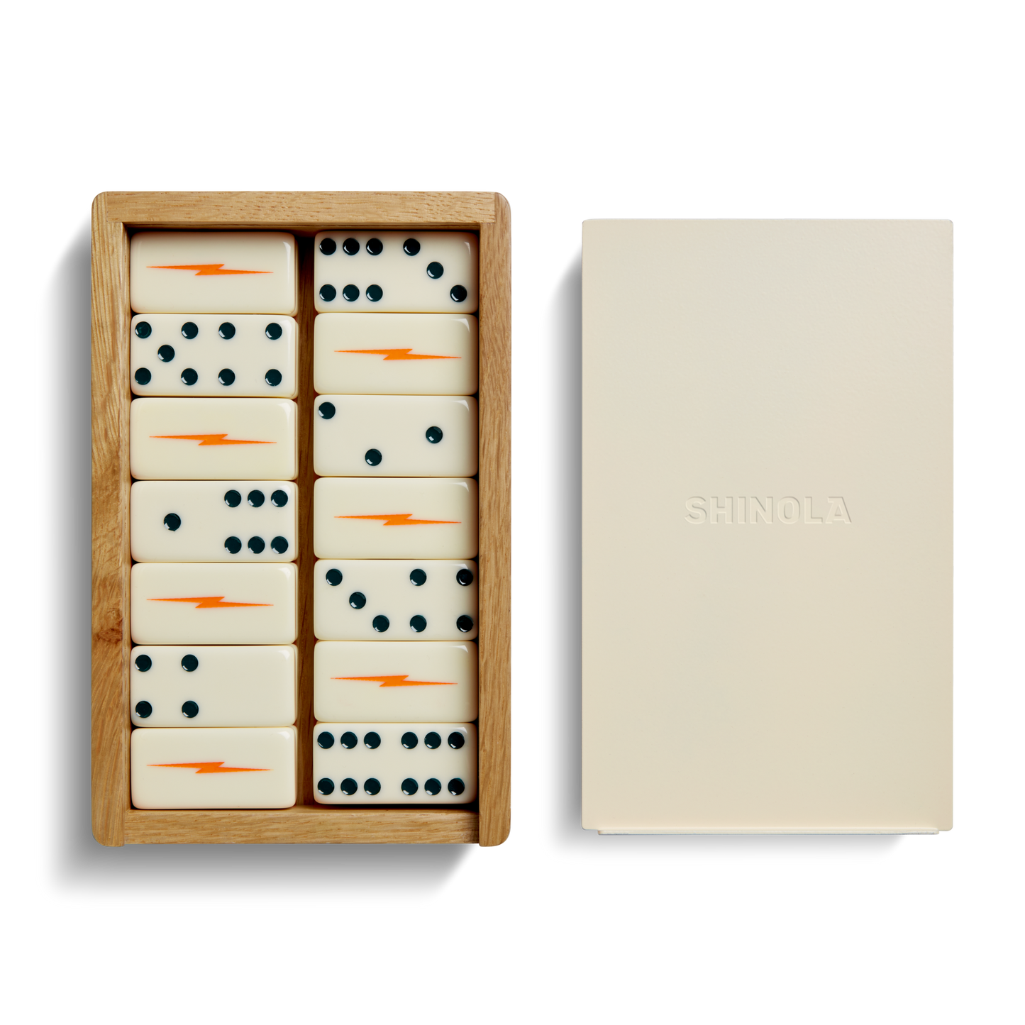 The Dominoes Set - Cream / Blue by Shinola features hand-painted tiles with blue dots and orange lightning bolts, housed in a wooden box next to a closed beige box embossed with the SHINOLA logo.