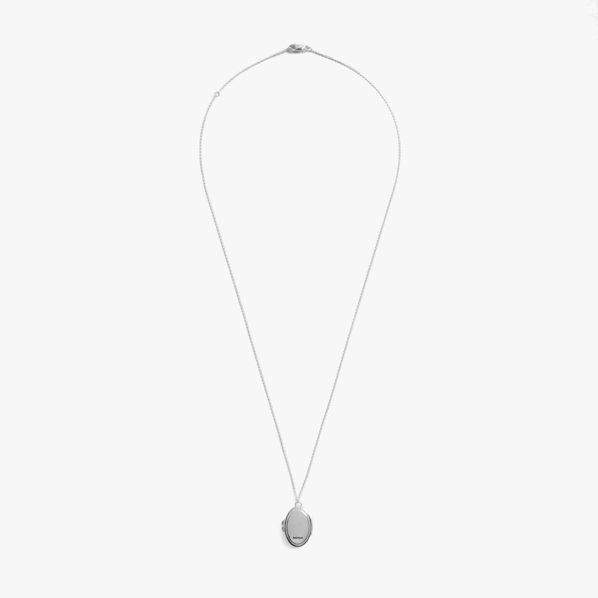The Shinola Heirloom Statement Locket Necklace features a sterling silver oval locket on a slim chain, elegantly displayed against a plain white background.