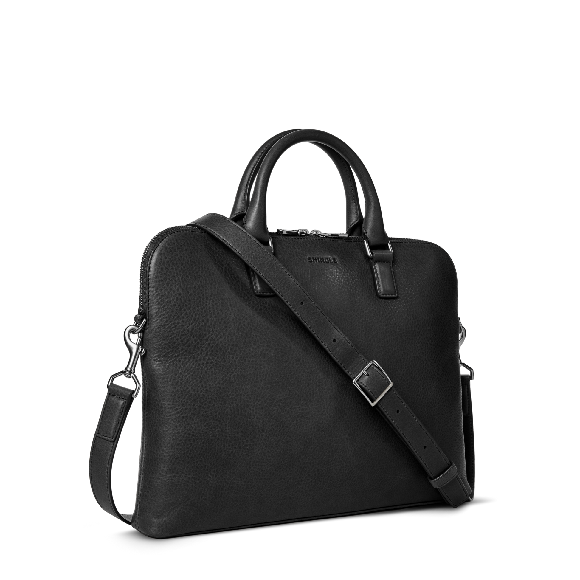 The Shinola Portfolio Briefcase - Black is crafted from European grain leather, featuring dual top handles, a detachable adjustable shoulder strap, zippered top, subtle front branding, and a slim minimalist design.