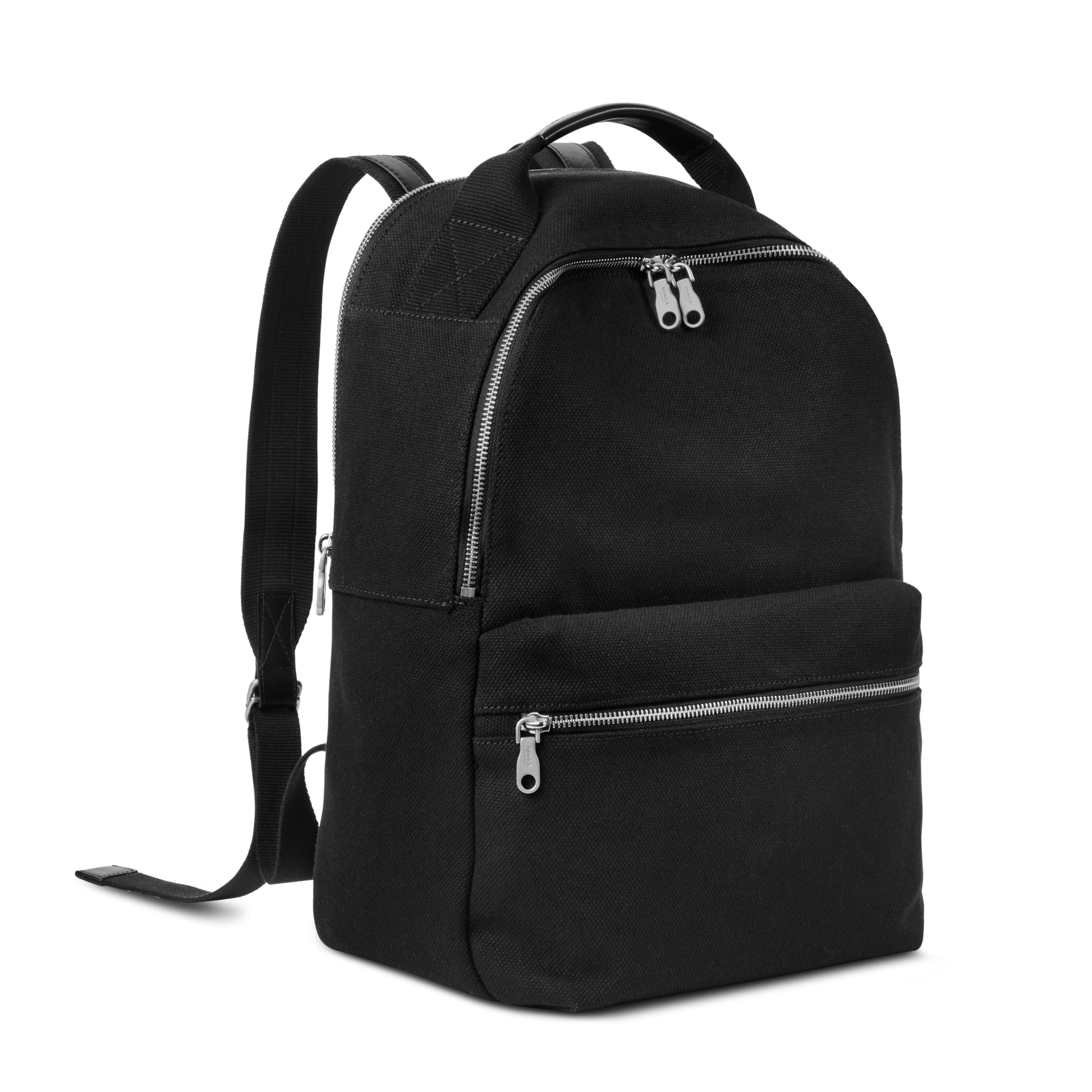 The Shinola Runwell Canvas Backpack in black features silver zippers, a front zip pocket, two adjustable shoulder straps, and a top handle—shown on a plain white background as a durable choice for everyday use.