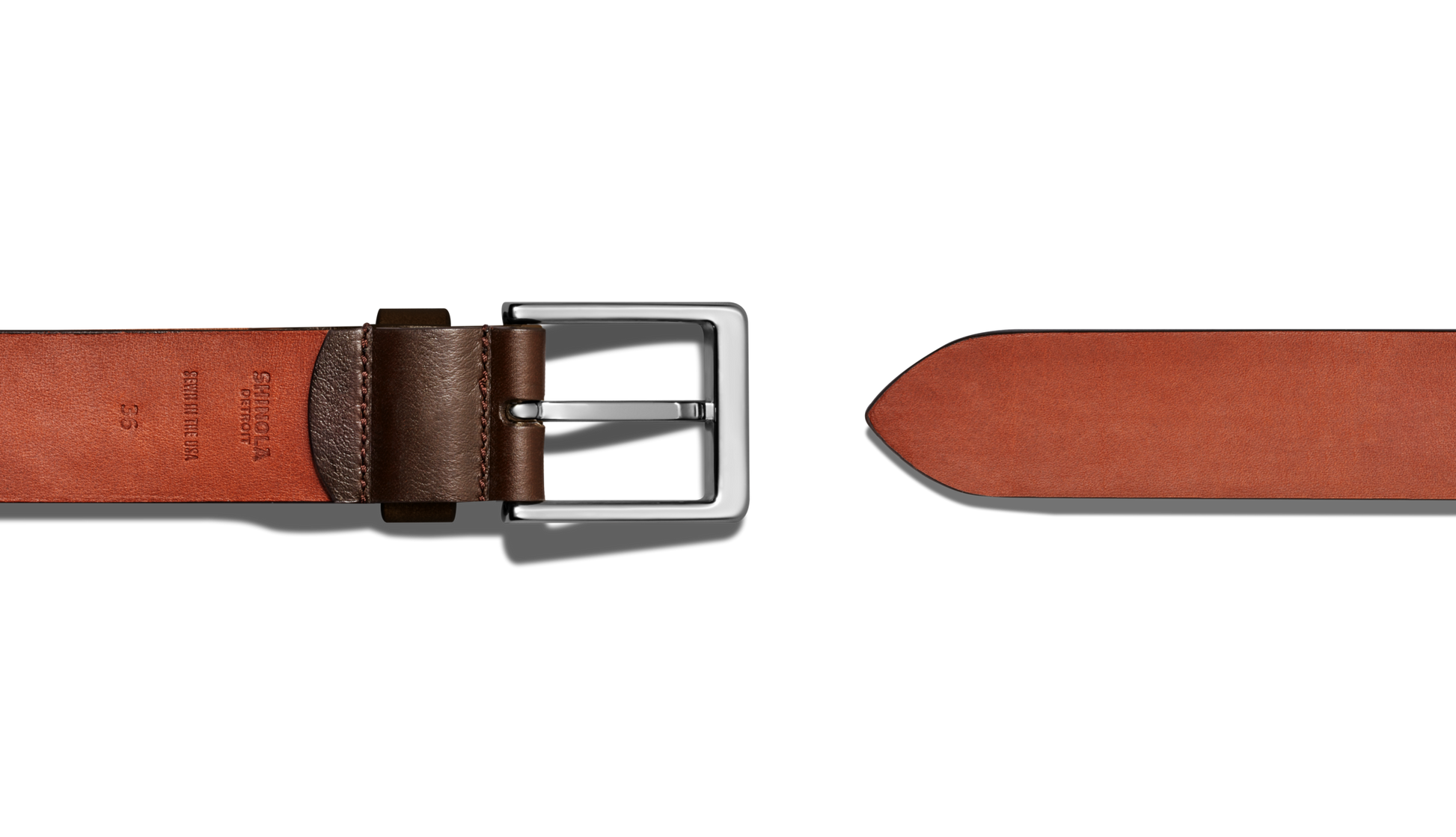 The Shinola 1 1/2" Lightning Bolt Keeper Belt in Deep Brown, featuring silver-tone hardware and a rectangular buckle, is shown laid flat on a white background. This casual belt includes a pointed tip and embossed inner text for detail.