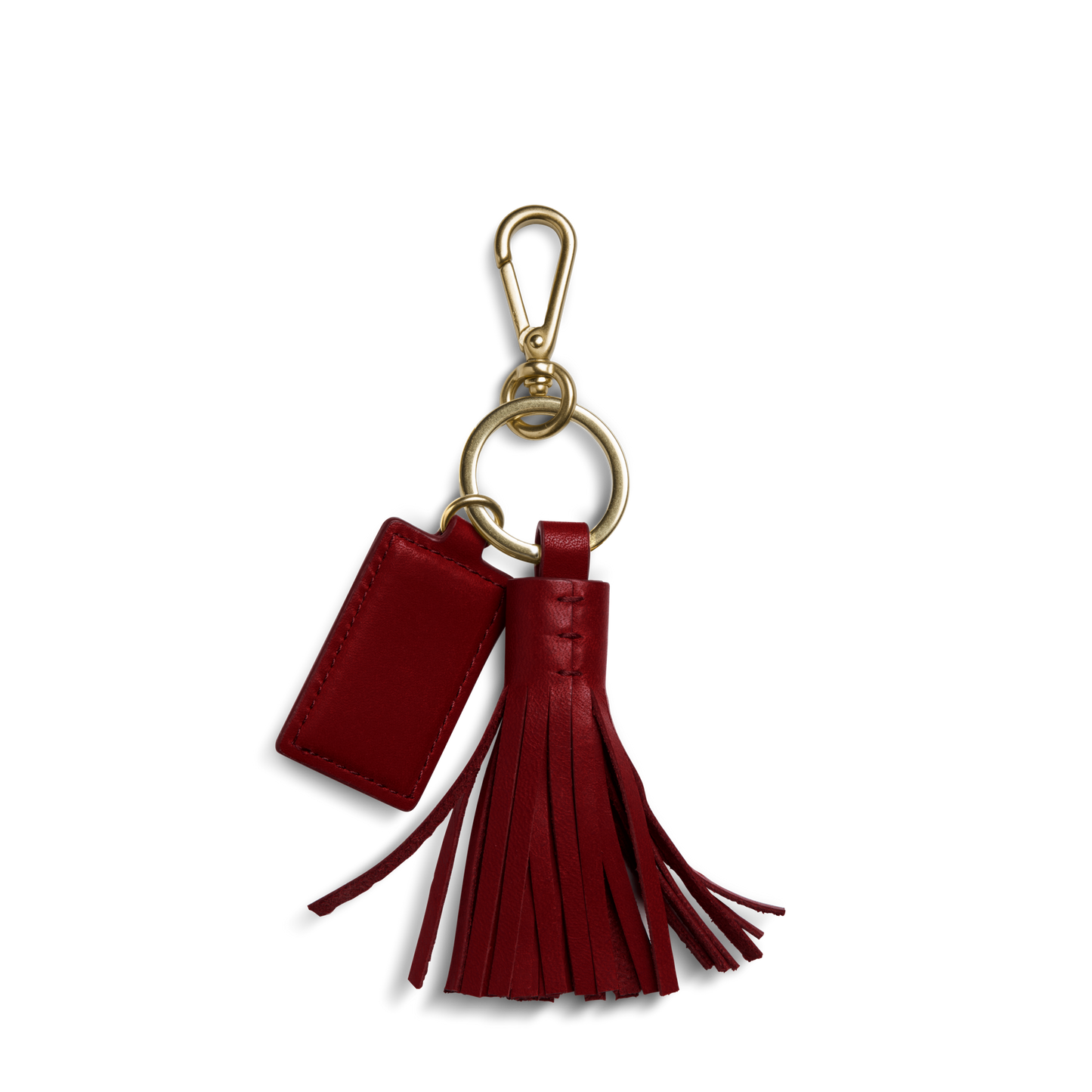 The Shinola Leather Tassel Keychain - Ruby features a red natural leather tassel and a rectangular monogrammable tag, attached to a gold keyring and clasp, displayed on a white background.