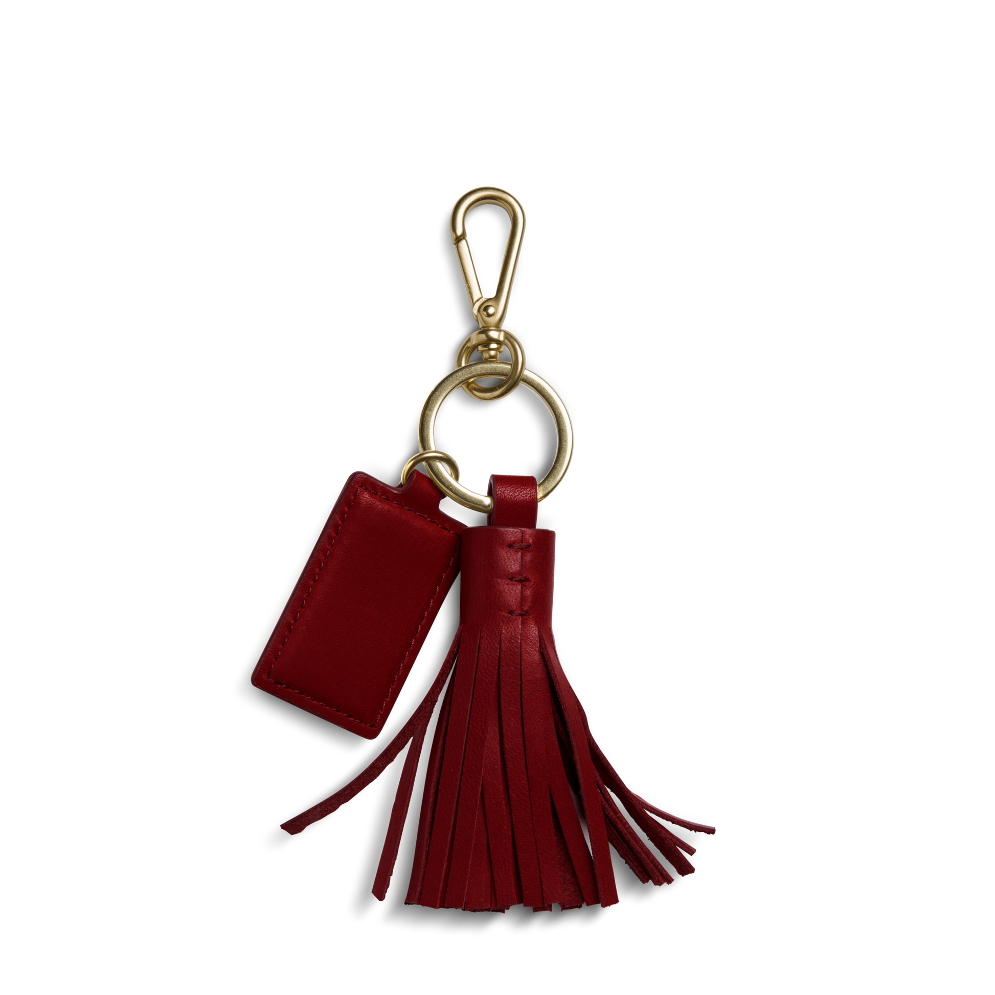 The Shinola Leather Tassel Keychain - Ruby features a red natural leather tassel and a rectangular monogrammable tag, attached to a gold keyring and clasp, displayed on a white background.