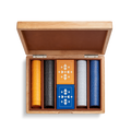 The Shinola Lacquered Wood Poker Set in Cream/Blue features a leather-lined case with an open lid, custom poker chips in yellow, black, white, and blue, plus two decks of geometric-patterned cards—one orange and one blue.