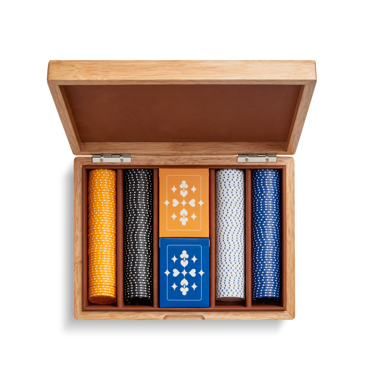 The Shinola Lacquered Wood Poker Set in Cream/Blue features a leather-lined case with an open lid, custom poker chips in yellow, black, white, and blue, plus two decks of geometric-patterned cards—one orange and one blue.