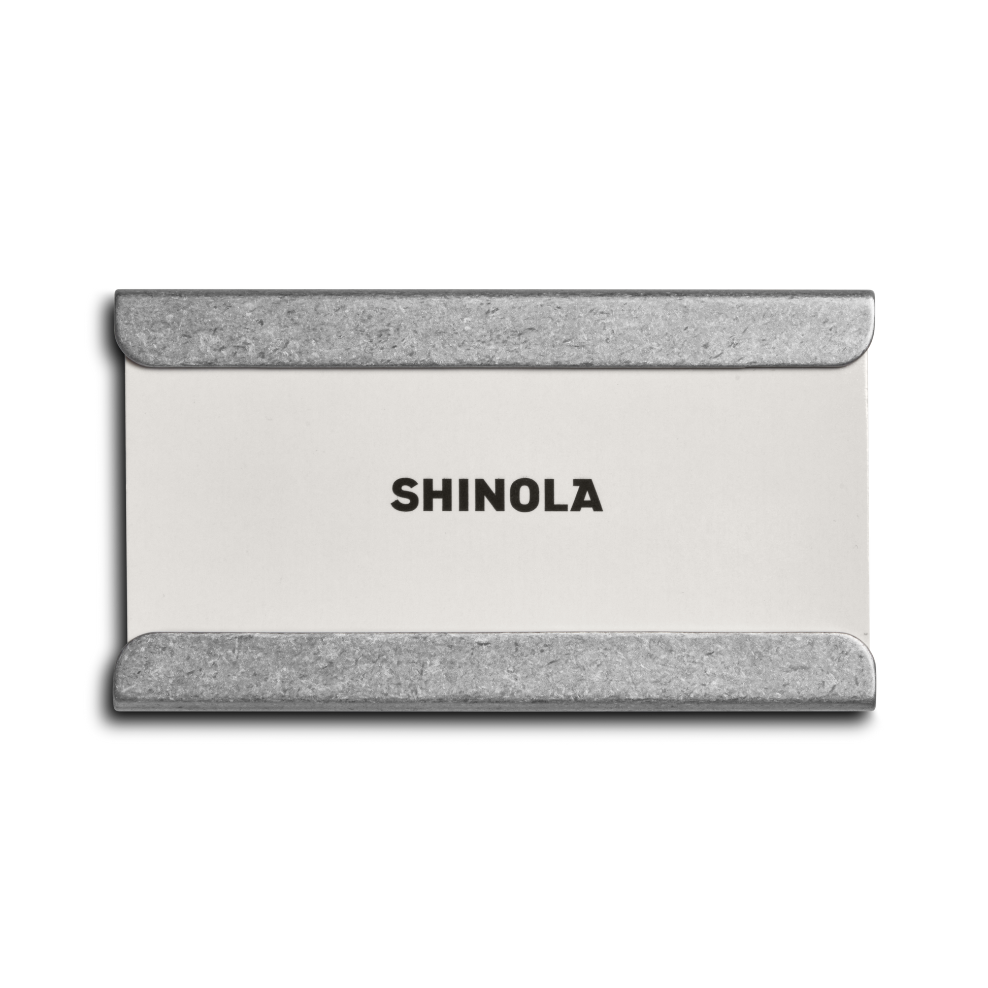 A rectangular white card with SHINOLA in bold black, framed by silver metal corners like the Aluminum Matchbox Set by Shinola, shown on a plain white background.