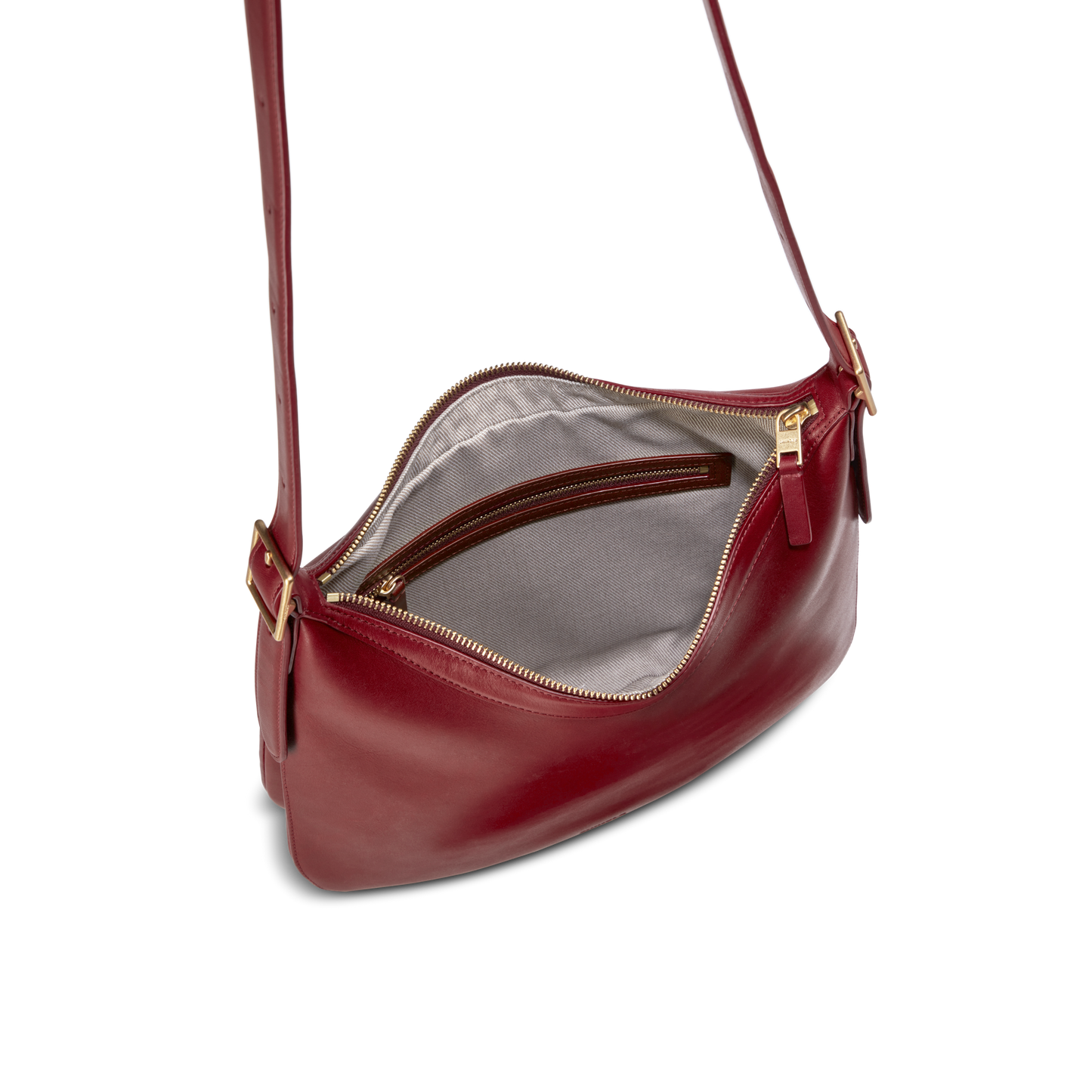 The Shinola Medium Bixby Crossbody - Ruby features red natural leather, a gold zipper, gray fabric lining with an inner zip pocket, and an adjustable strap with gold hardware for versatile style.