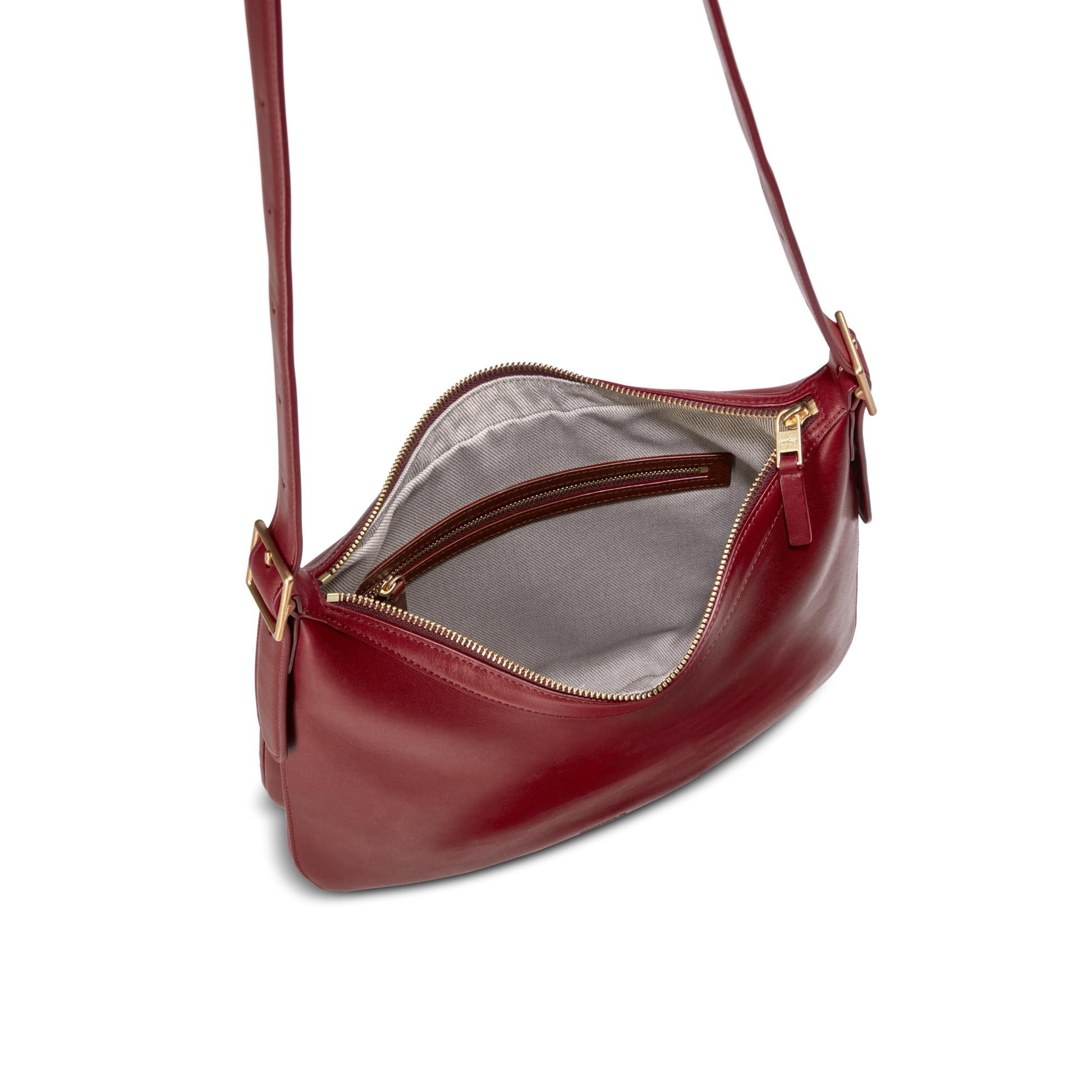 The Shinola Medium Bixby Crossbody - Ruby features red natural leather, a gold zipper, gray fabric lining with an inner zip pocket, and an adjustable strap with gold hardware for versatile style.