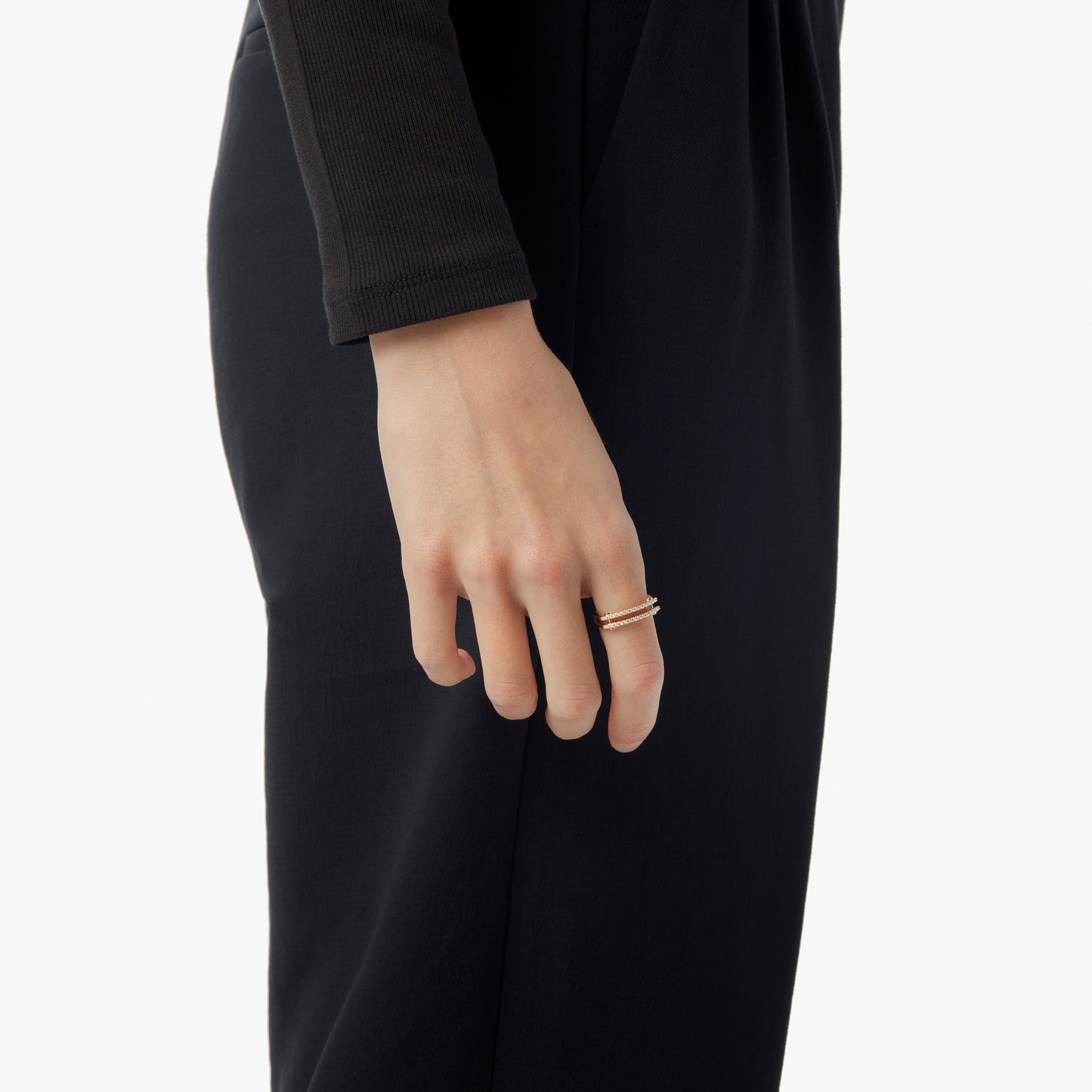 A person in a black long-sleeve outfit, shown shoulder to knee, displays the Shinola Diamond Pave Rivet Double Row Ring in yellow gold on their index finger.