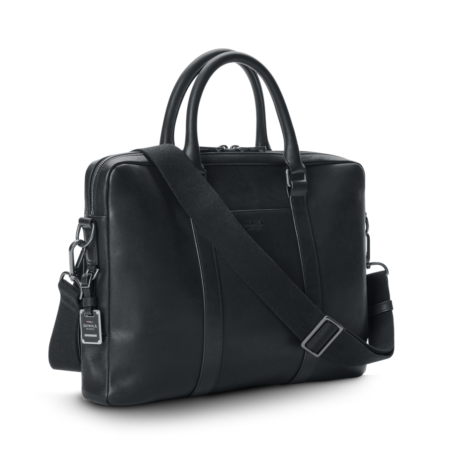 The shinola.momputer Briefcase in black features two handles, a removable adjustable shoulder strap, and a small luggage tag, shown against a plain white background.