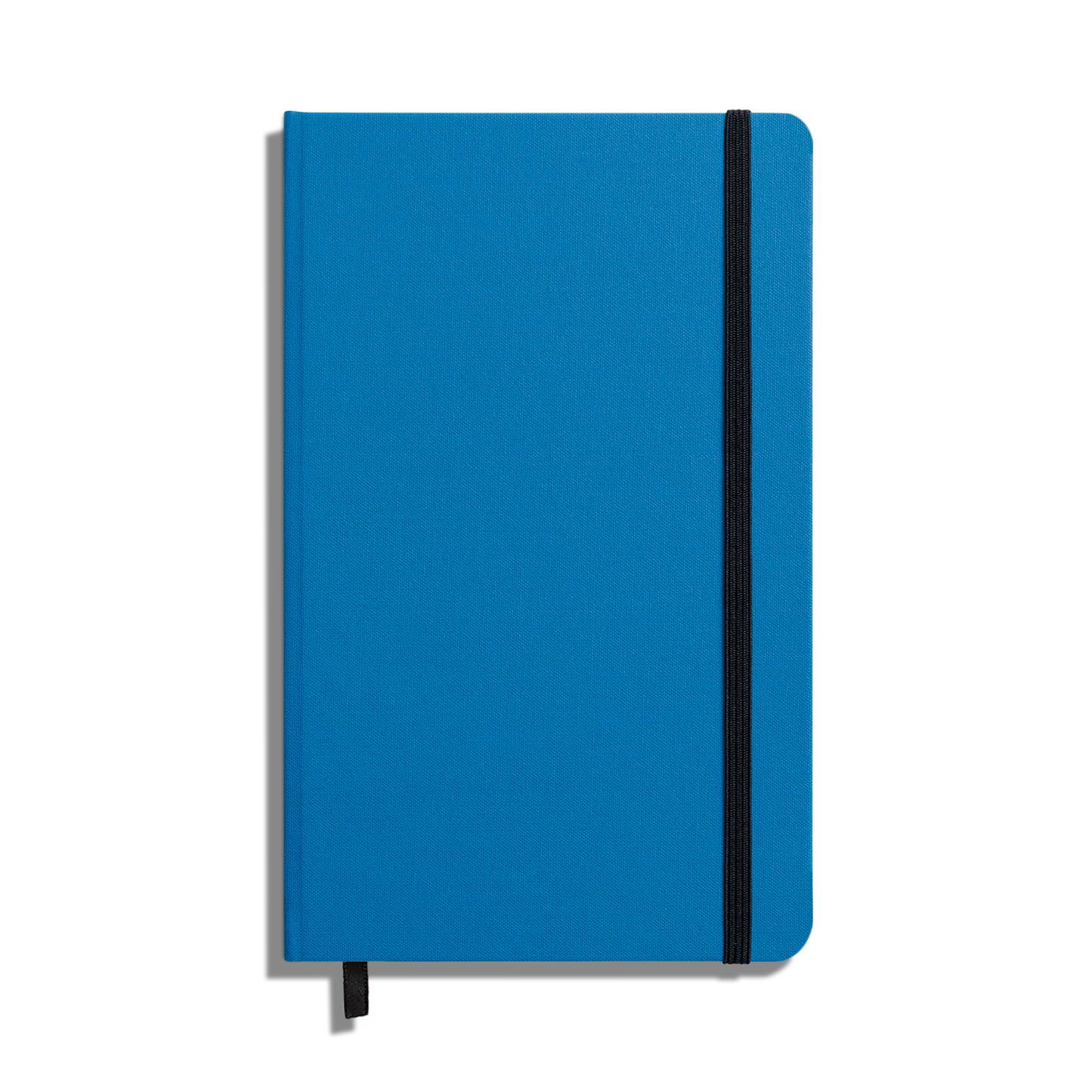 The Shinola Medium Hard Ruled Journal - Cobalt is a closed blue hardcover notebook with acid-free paper, a vertical black elastic band, and a matching ribbon bookmark, shown on a white background.
