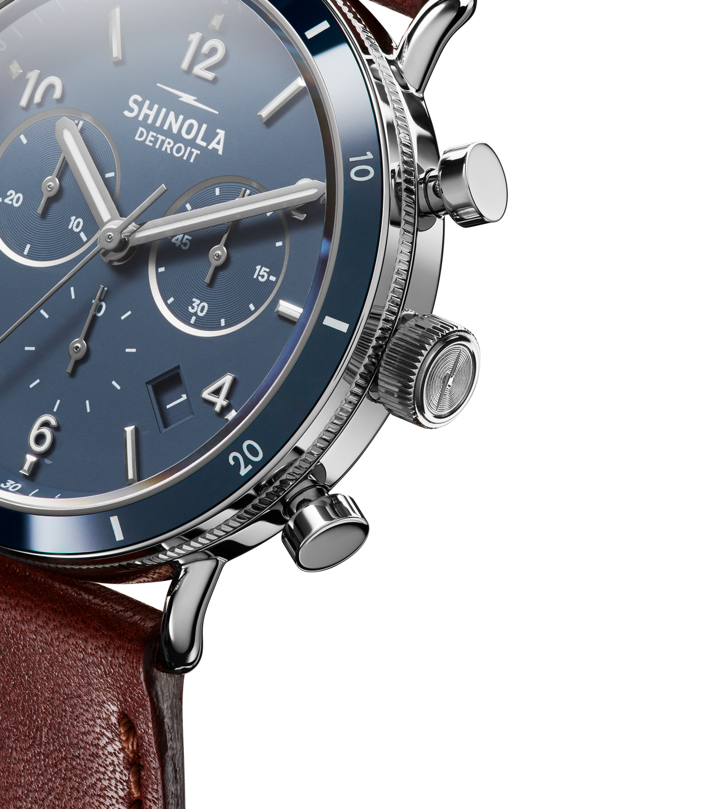 Close-up of the Shinola Canfield Sport Chronograph Watch - Midnight Blue, featuring a blue chronograph dial with silver hour markers, three subdials, a brown leather strap, polished metal case, and side buttons.