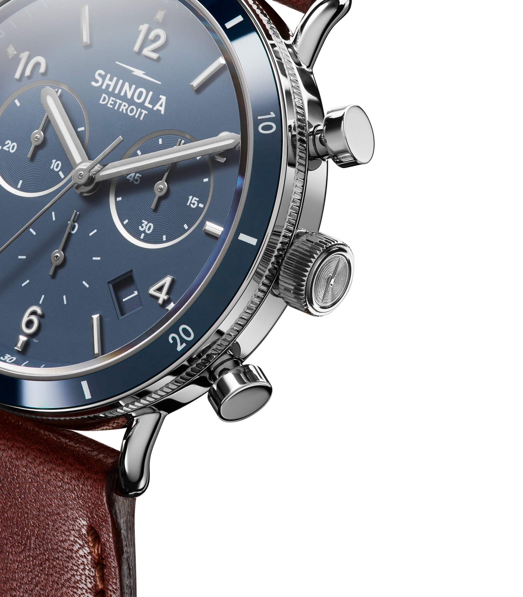 Close-up of the Shinola Canfield Sport Chronograph Watch - Midnight Blue, featuring a blue chronograph dial with silver hour markers, three subdials, a brown leather strap, polished metal case, and side buttons.
