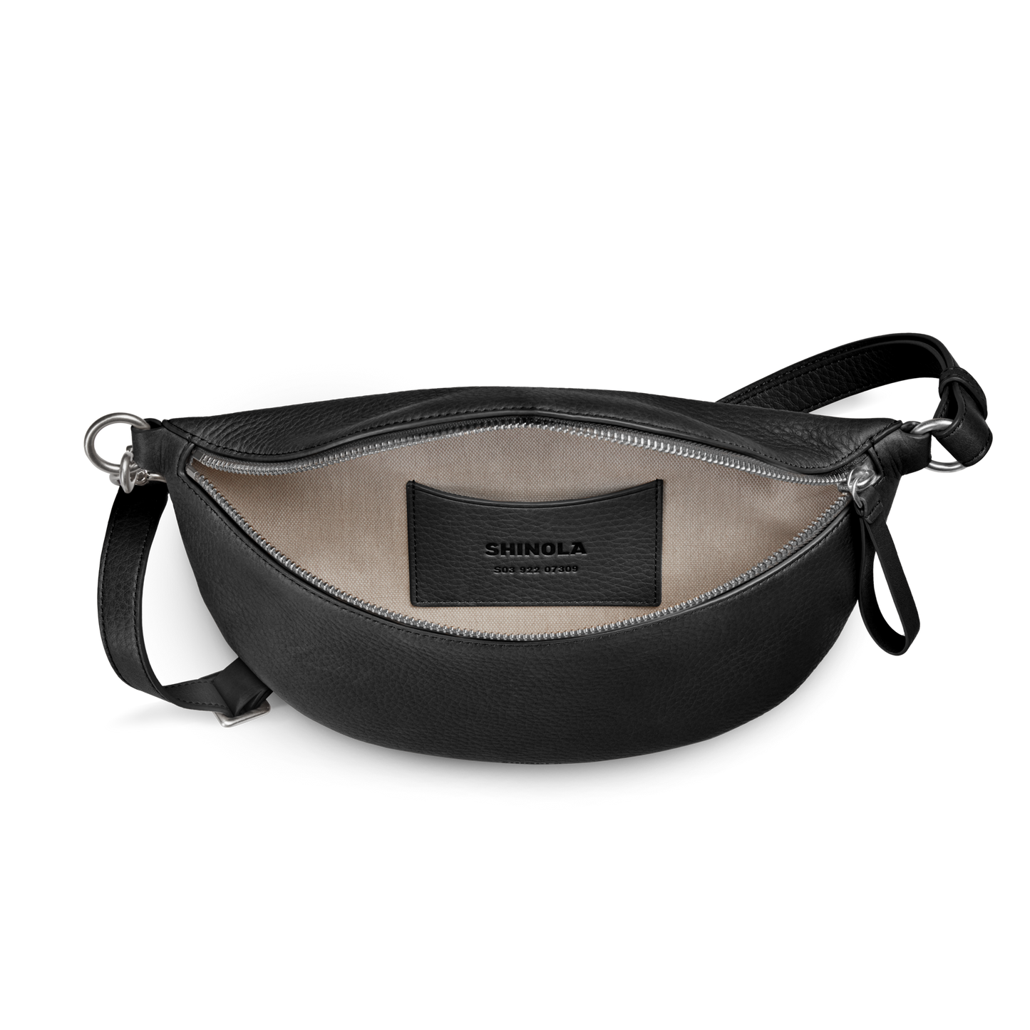 The Shinola Sling Bag - Black is a leather crossbody with a beige interior, small inside pocket, black Shinola patch, adjustable strap, and unzipped for easy access.