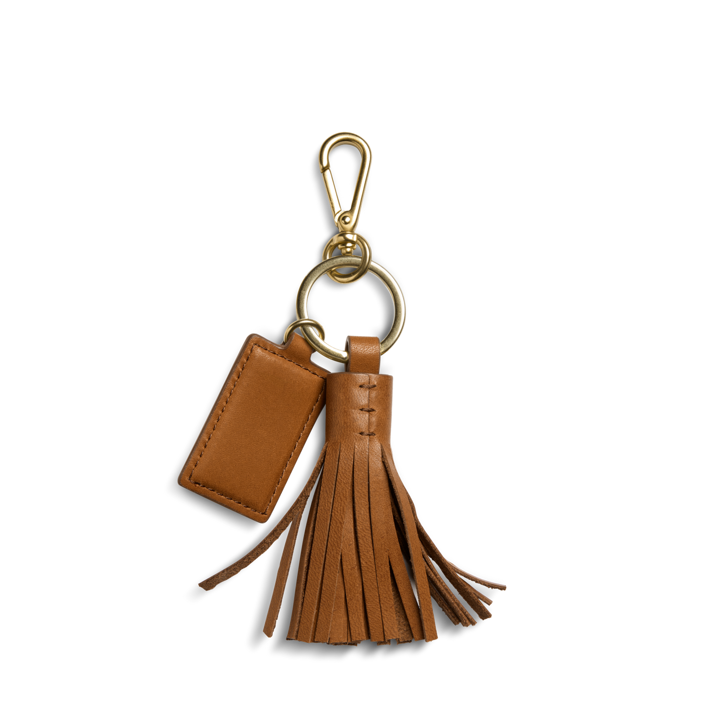 The Shinola Leather Tassel Keychain - Tan features a rectangular leather tag, gold clip, and leather tassel accents, shown against a plain white background.
