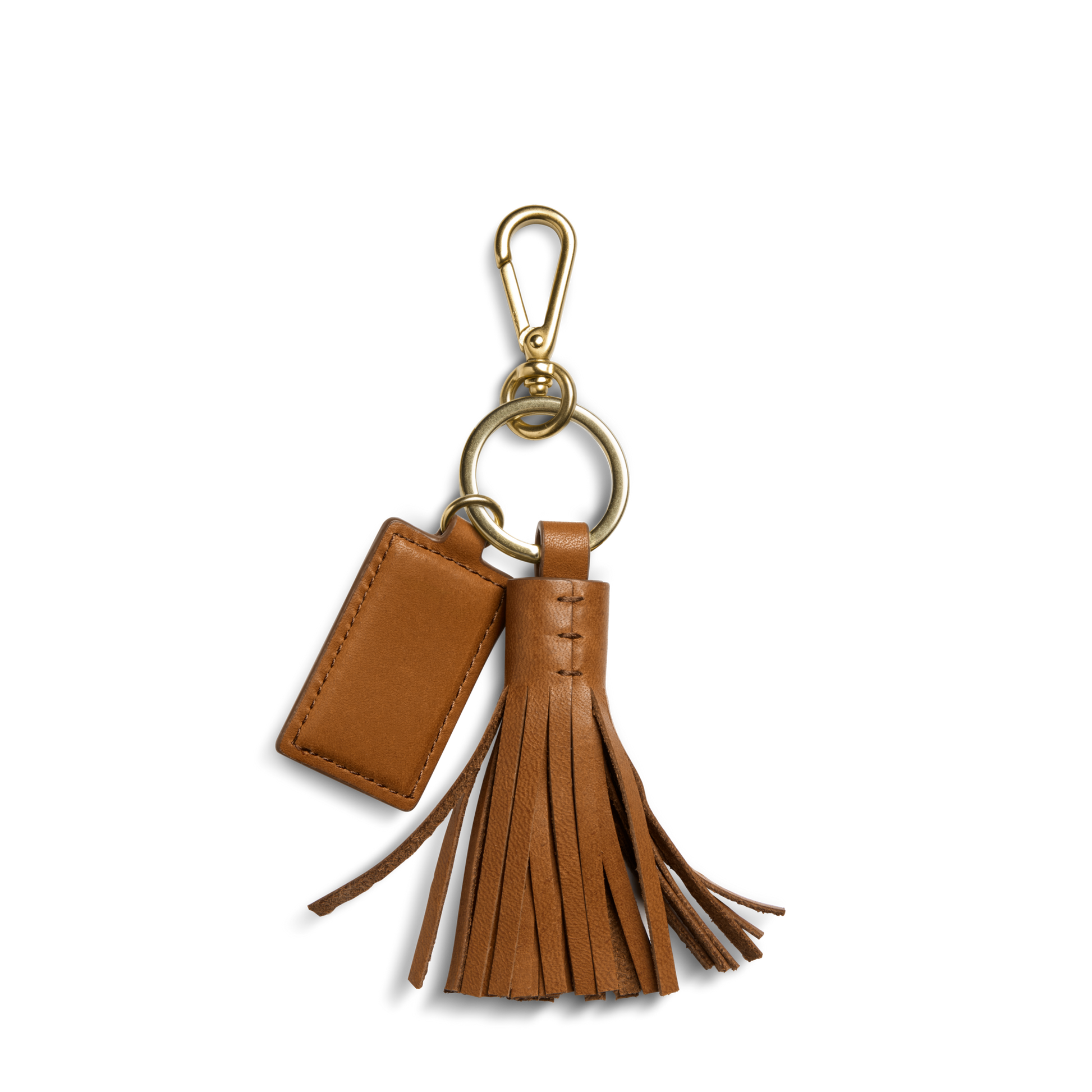 The Shinola Leather Tassel Keychain - Tan features a rectangular leather tag, gold clip, and leather tassel accents, shown against a plain white background.