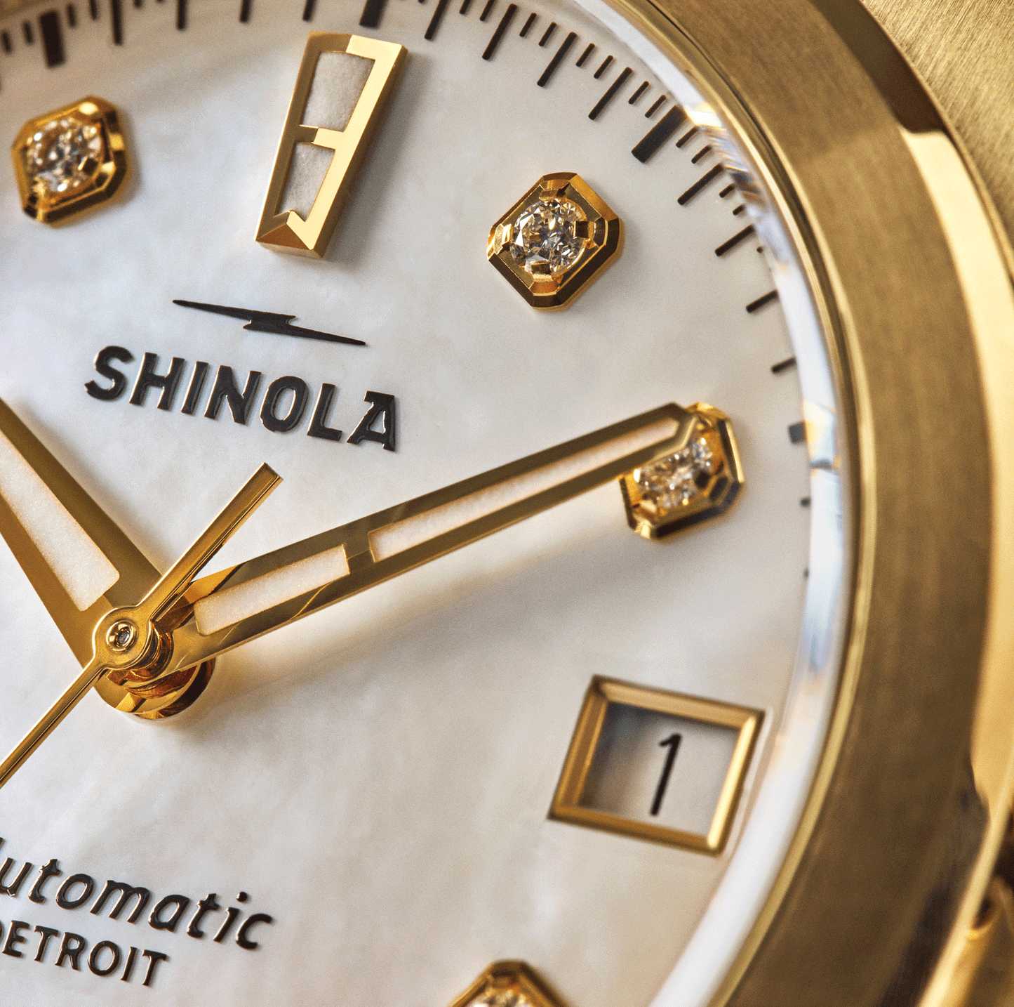 Close-up of a gold Shinola Circadian Monster Automatic Watch – Mother of Pearl Diamond, featuring a white mother-of-pearl face, gold hands, diamond indices, date display set to 1, and the partially visible word "Automatic" at the bottom.
