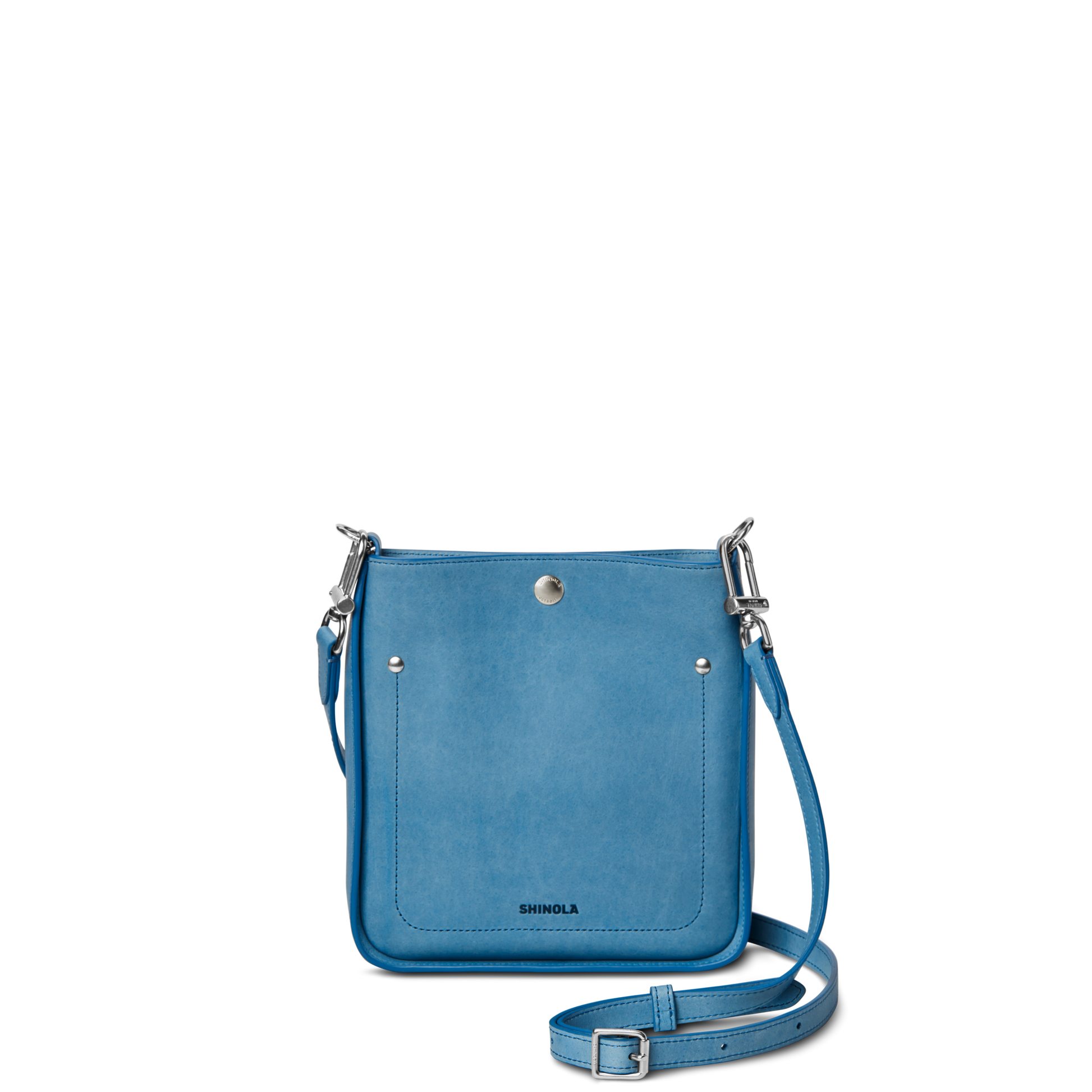 The Shinola Mini Pocket Crossbody Bag - River is a small, rectangular, light blue bag with a front pocket, silver hardware, and adjustable strap, shown against a plain white background.