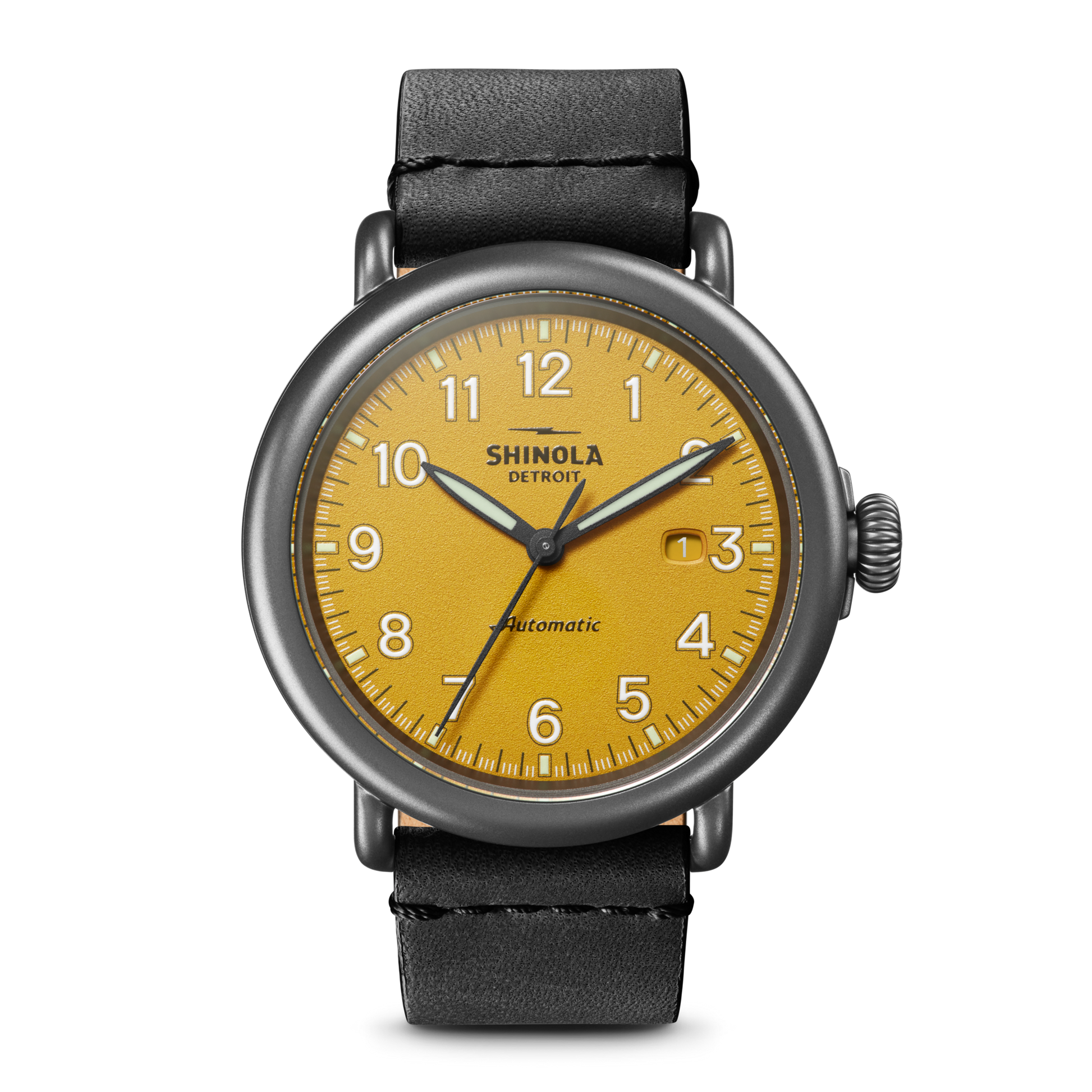 The Shinola Runwell Automatic Watch - Ochre features an ochre vellum-textured dial with black numerals, a date window at 3 o'clock, and a black leather strap. "Shinola" and "Automatic" are printed on the watch face.