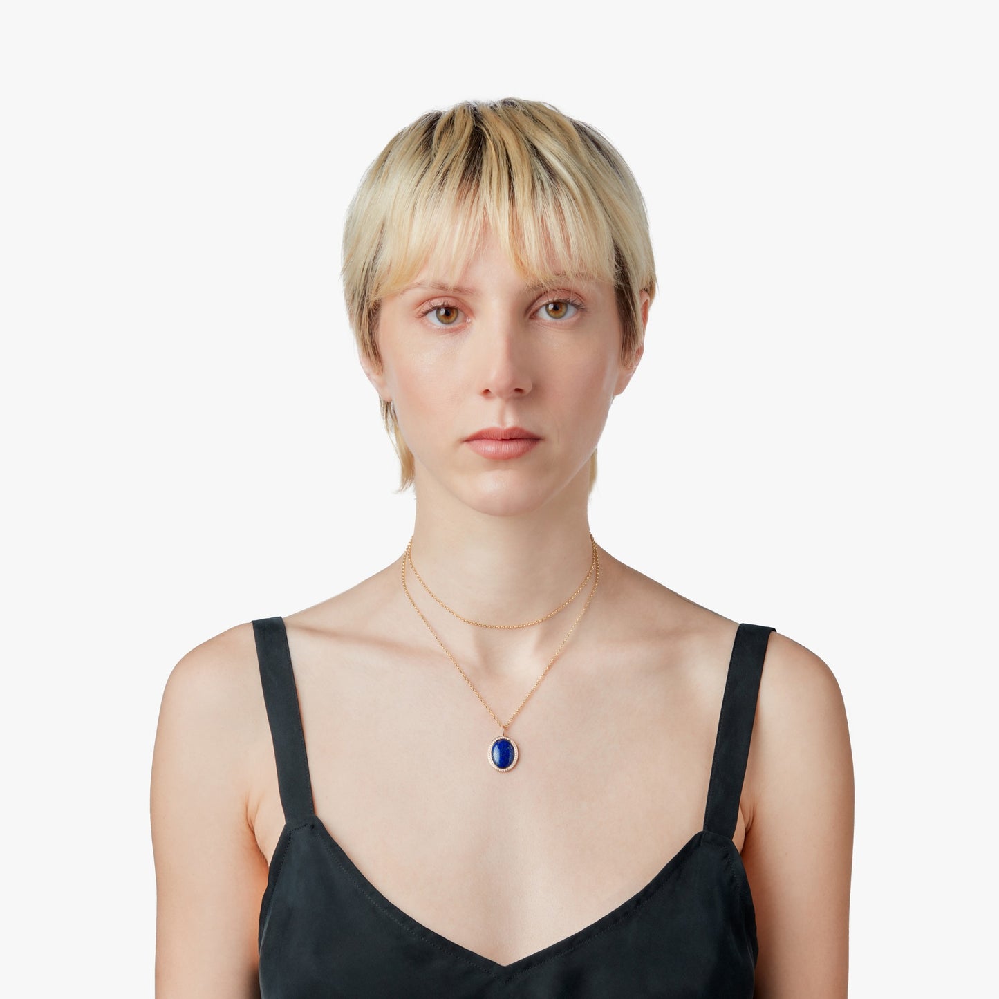 A person with short blonde hair wears a black sleeveless top and the Shinola Diamond Pave Lapis Pendant Necklace in yellow gold, posed against a plain white background.