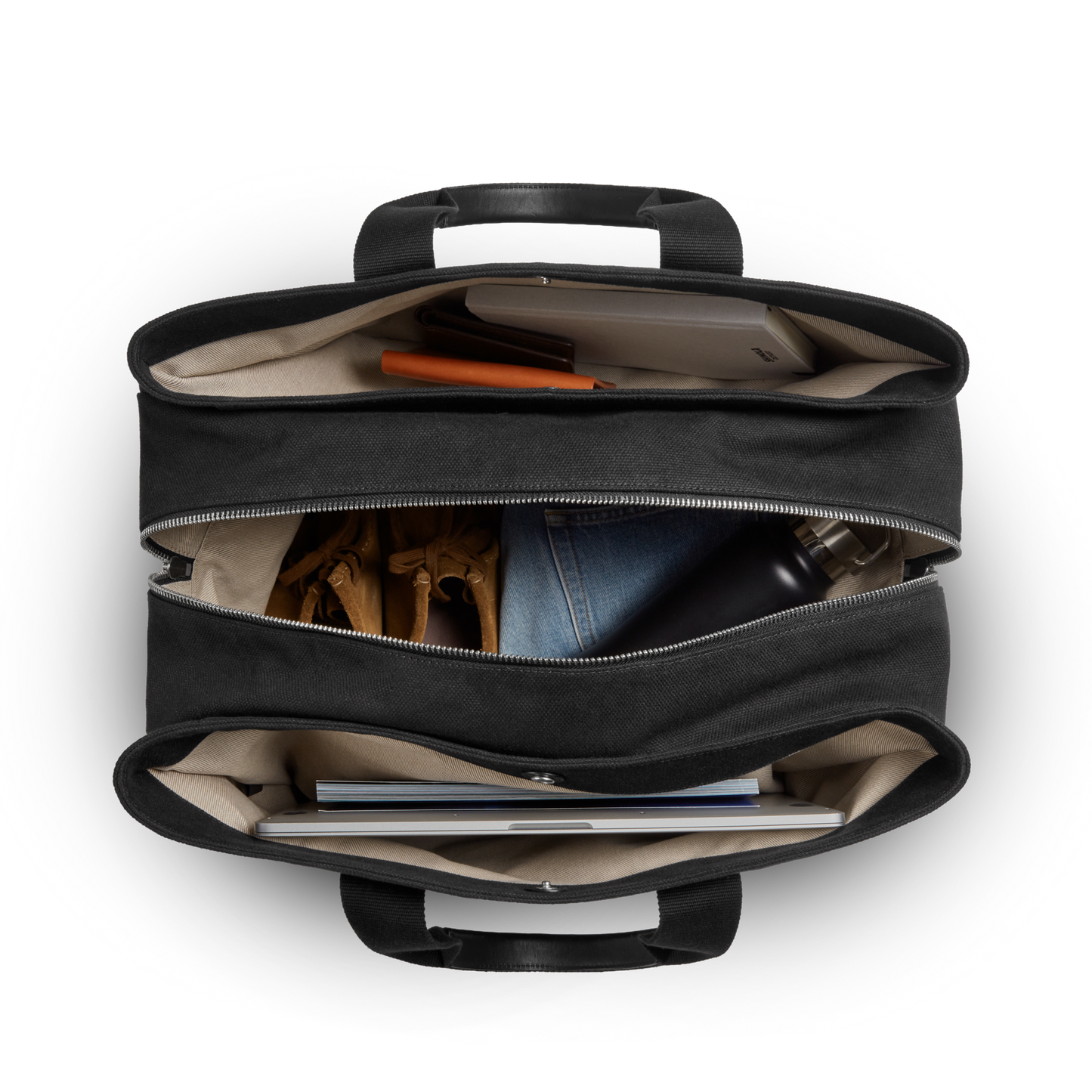 Top-down view of a Shinola Runwell Canvas Duffle Bag - Black with three zippered compartments, holding a notebook, orange pen, gloves, denim fabric, black water bottle, and a closed laptop—ideal as a TSA carry-on.