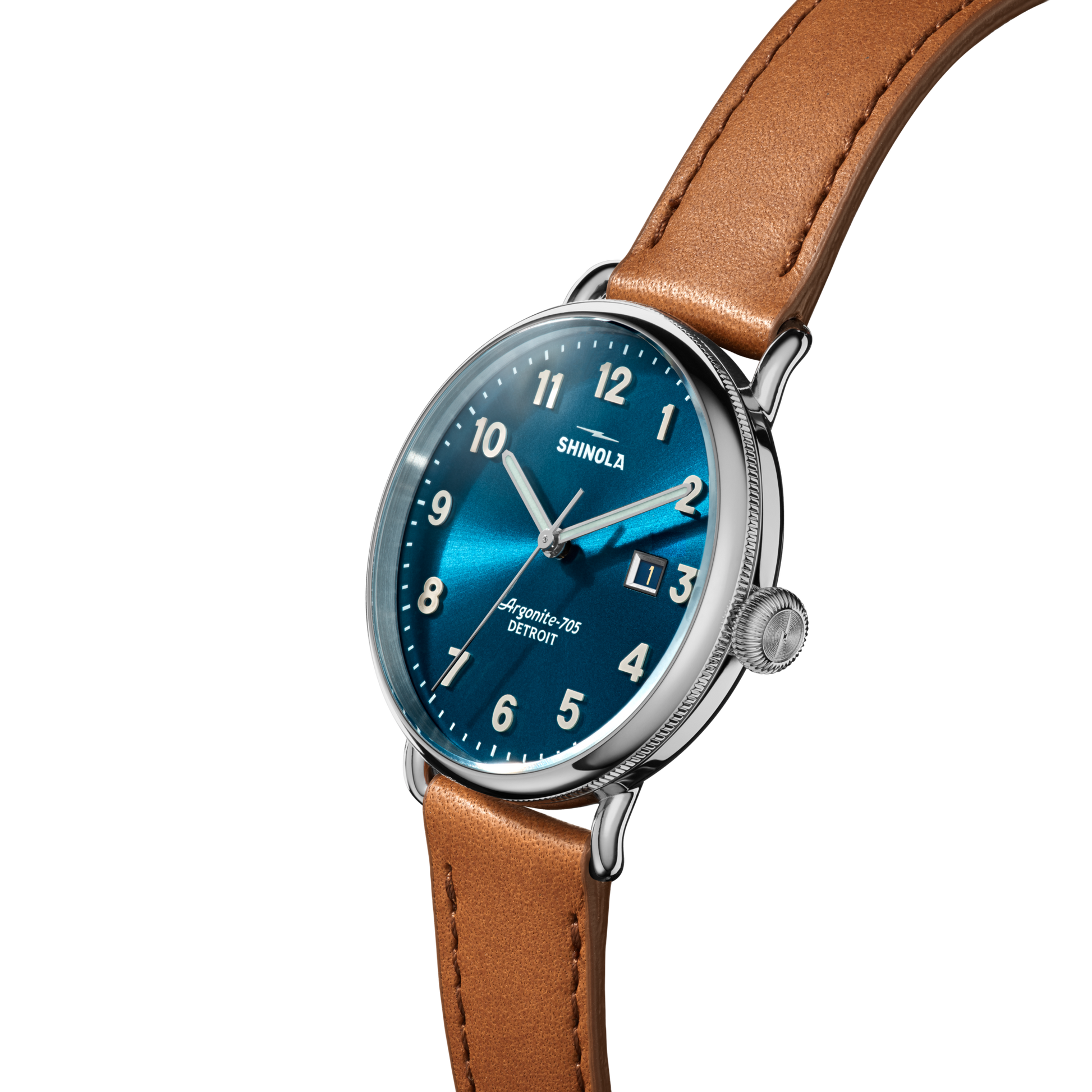 The Shinola Canfield Watch features an astro blue dial with white hour markers, a date display, a stainless steel case, and a brown leather strap. The watch is angled on a white background, displaying the Shinola brand name on the face.