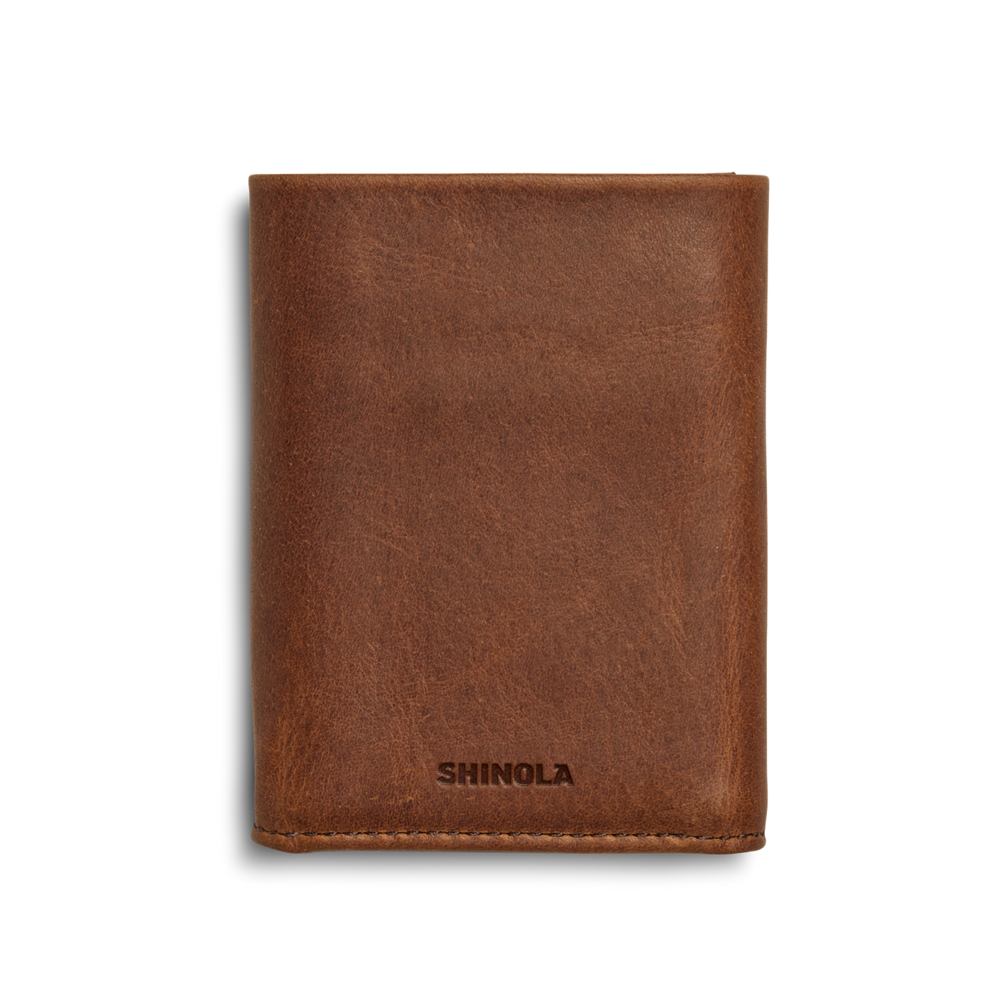 A medium brown Trifold Wallet by Shinola is shown closed, with "SHINOLA" embossed at the bottom center on the front against a plain white background.