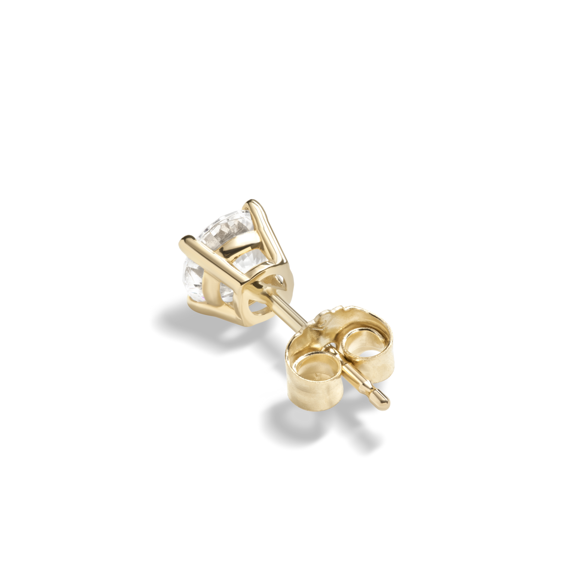 The Shinola 1 Carat Round Diamond Studs in yellow gold feature a clear gemstone in a prong setting, shown lying on its side against a plain white background—perfect for lovers of classic earrings.