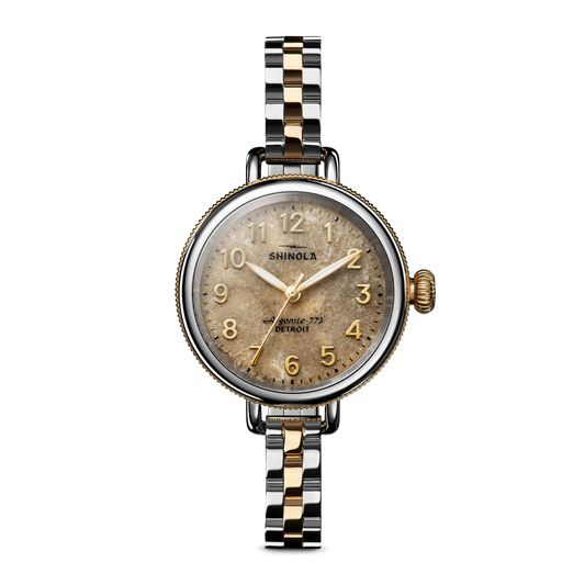Assembled in Detroit, the Shinola Birdy Watch - Petoskey features a round vintage-style gold-tone face with gold numerals and a two-tone gold and stainless steel link band, shown on a plain white background.