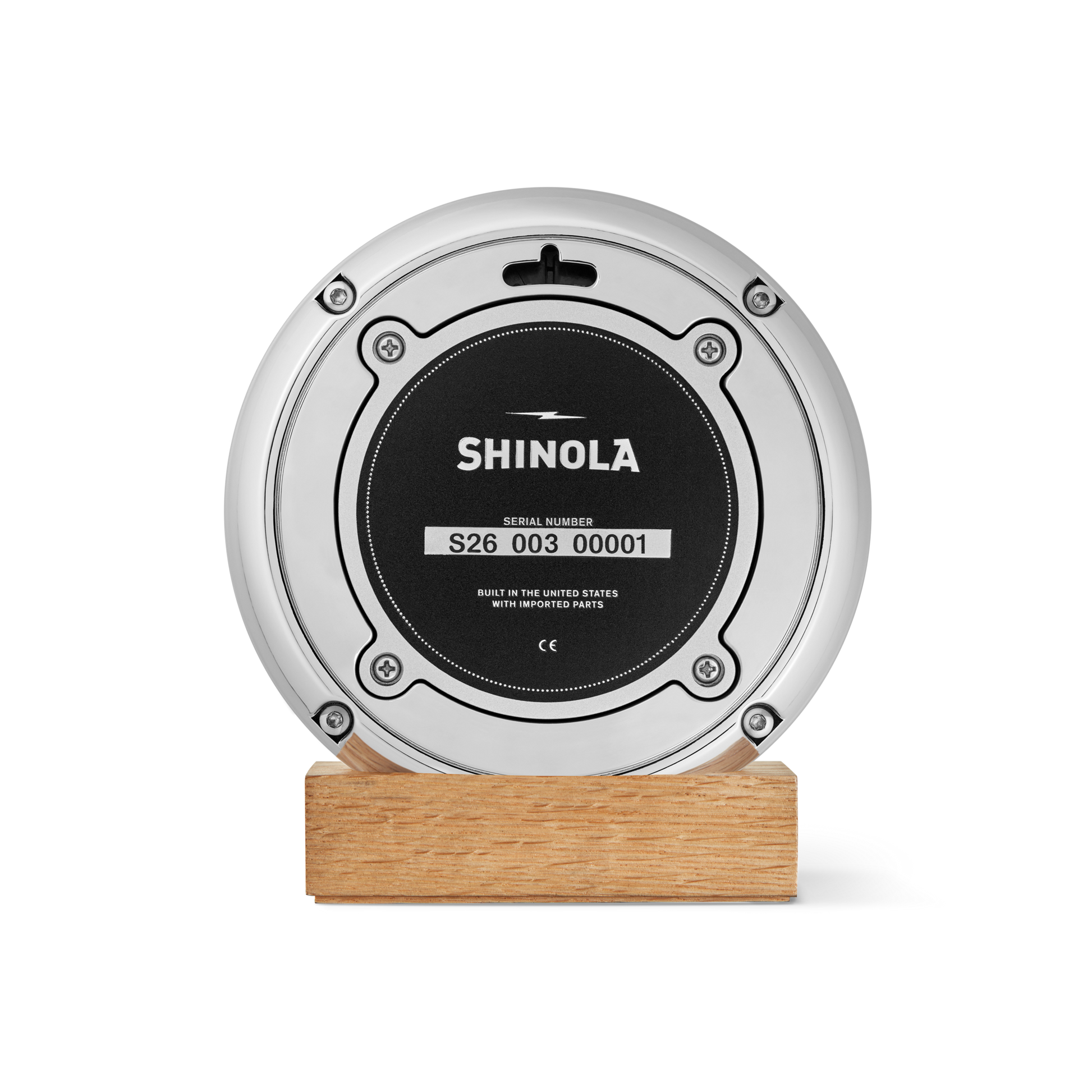 A round, silver Shinola 6" Runwell Clock with a blue faceplate, mounted on a rectangular wooden base, stands out against a white background—an elegant nod to University of Michigan’s wolverine blue heritage.